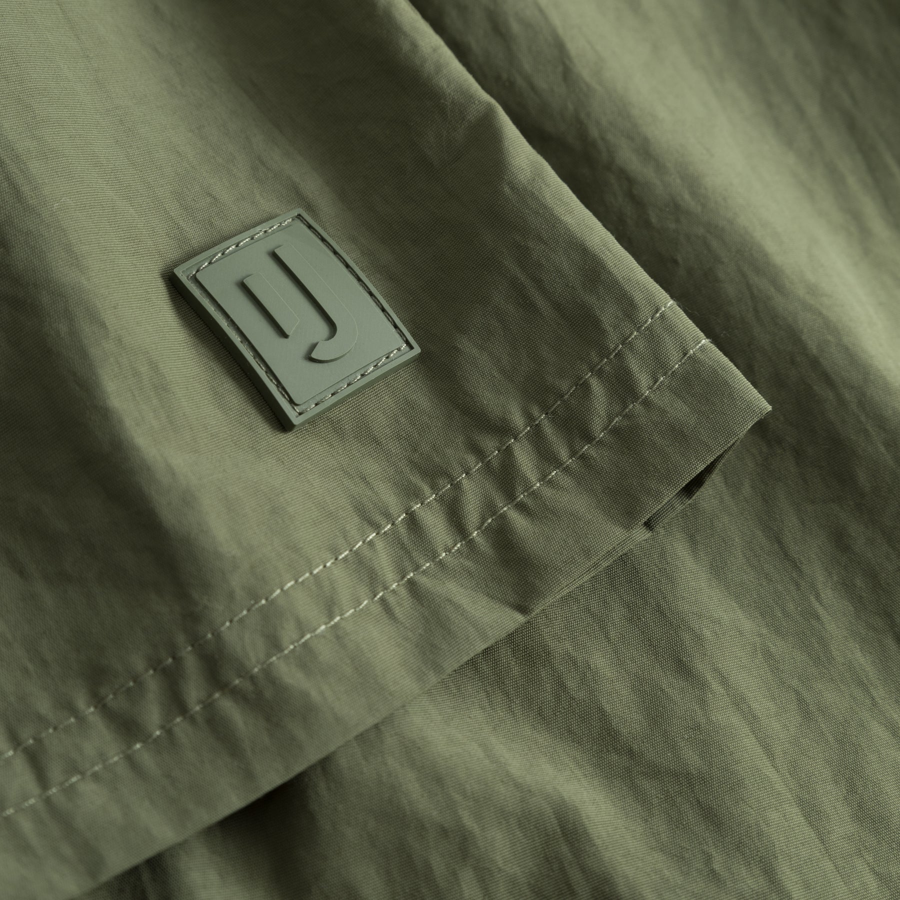 Detailaufnahme der olivgrünen Badehose 'Jay' mit einem rechteckigen Logo-Label