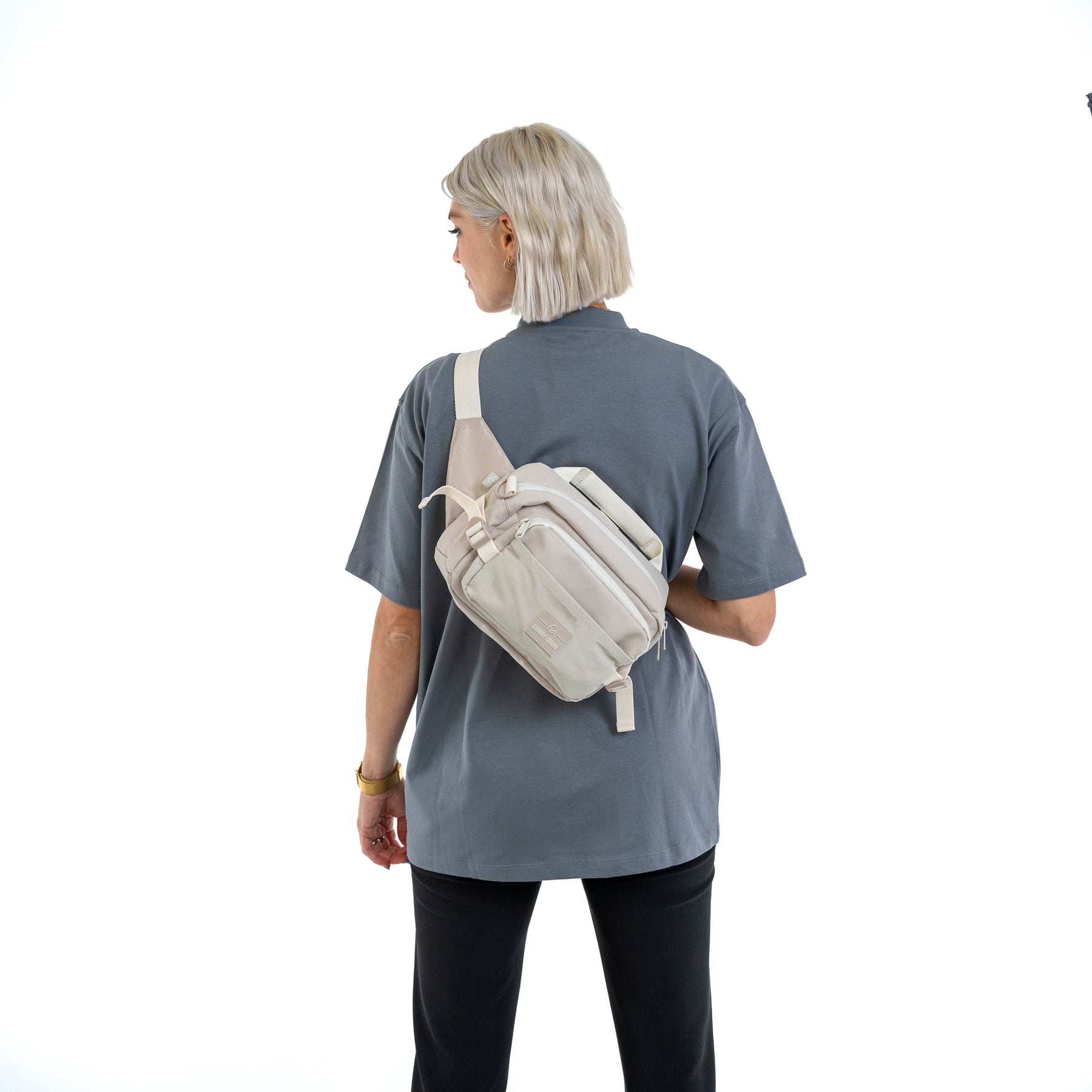 Frau von hinten mit kurzer, blonder Frisur trägt beige Bauchtasche 'Travis' quer über den Rücken