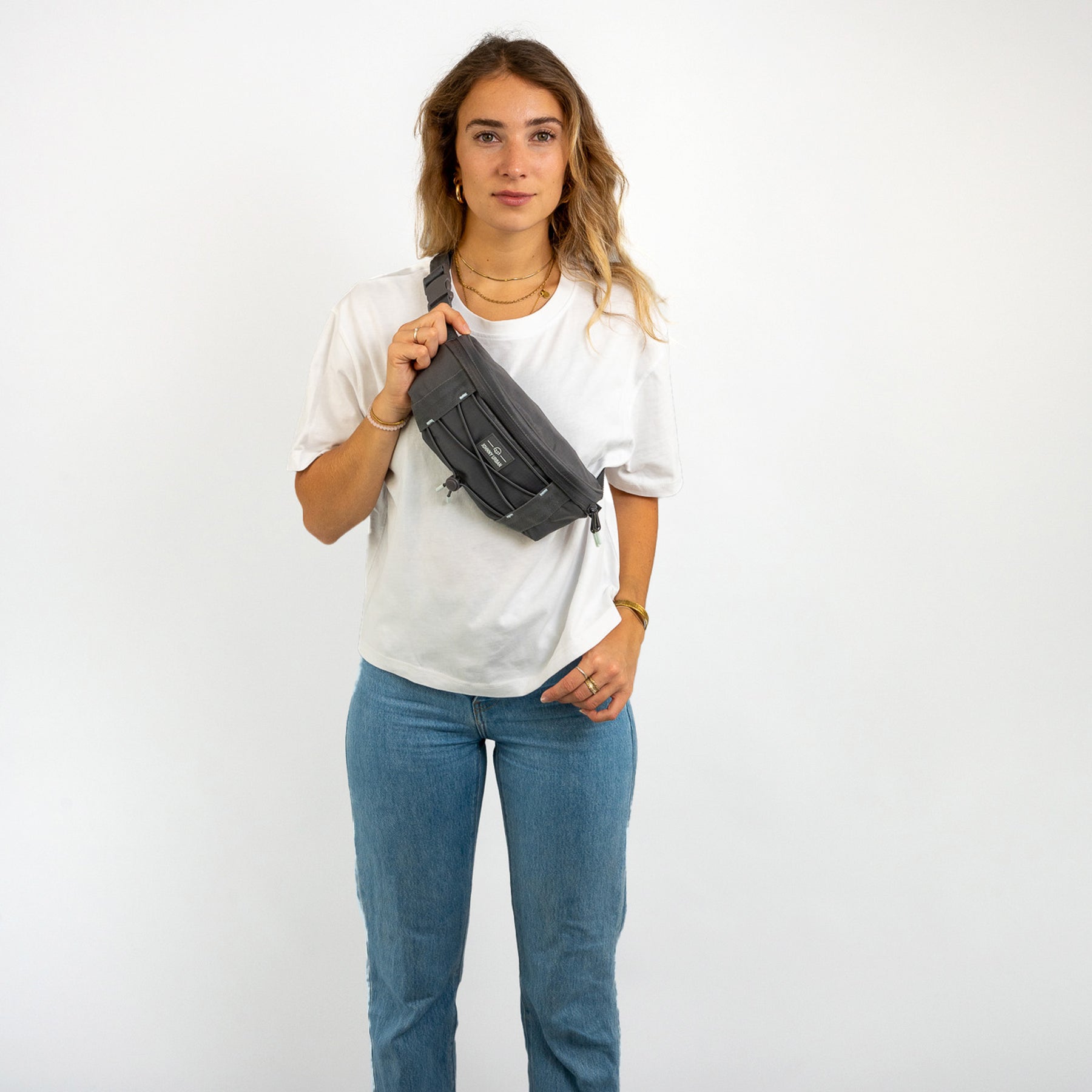 Frau trägt graue Bauchtasche 'Devin' von Johnny Urban über weißem T-Shirt und blauen Jeans