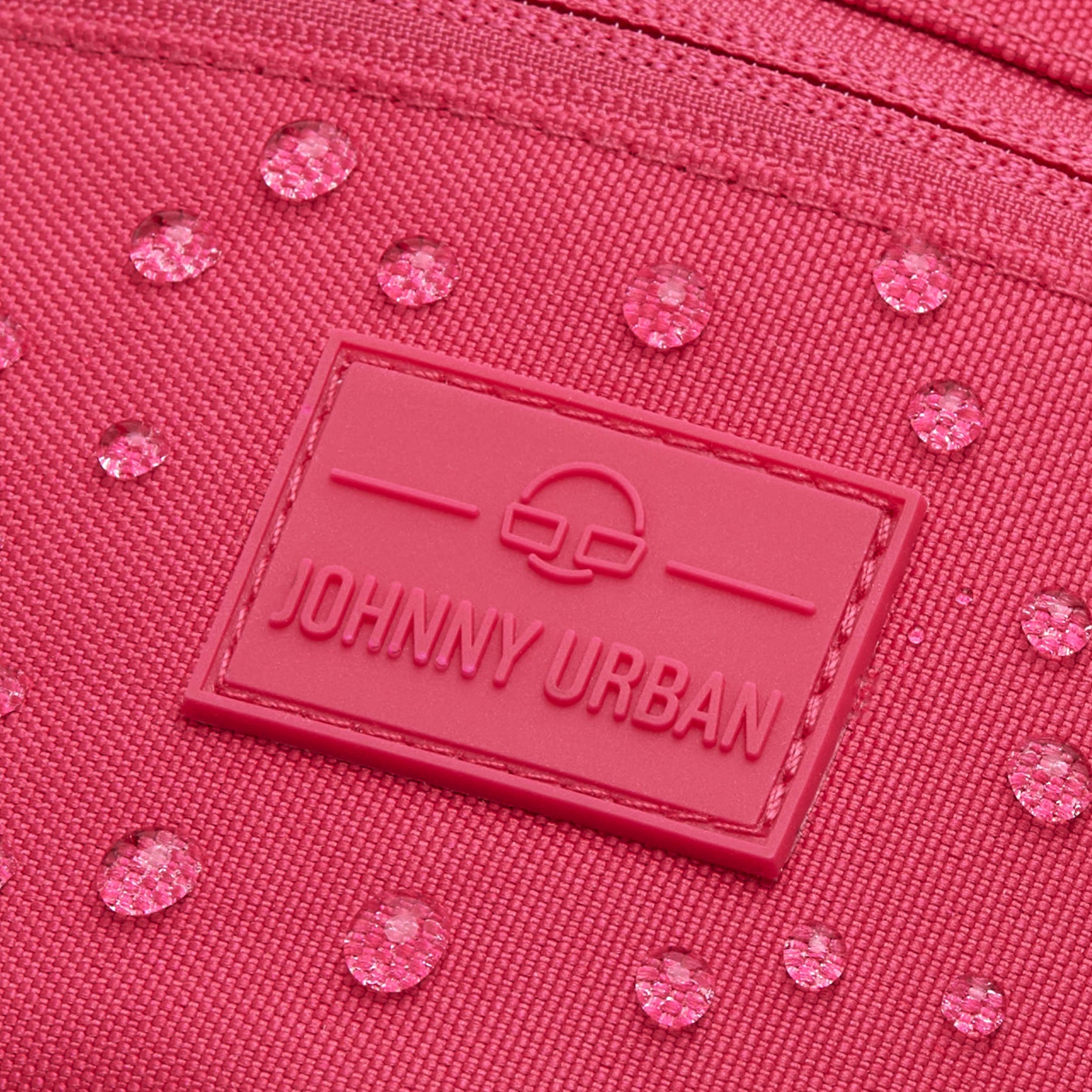 Nahaufnahme der pinken Bauchtasche ‚Erik Small‘ von Johnny Urban mit sichtbaren Wassertropfen auf dem Material