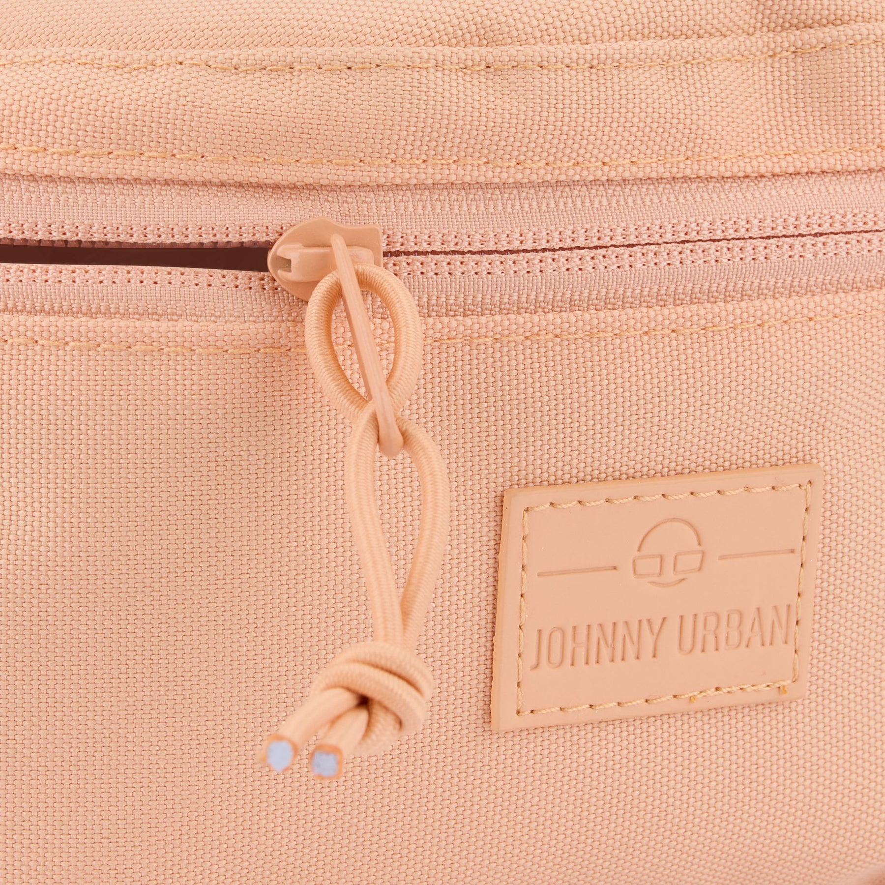 Detailansicht des Reißverschlusses und des Lederlogos der Johnny Urban Bauchtasche 'Erik Small' in Pfirsichfarben
