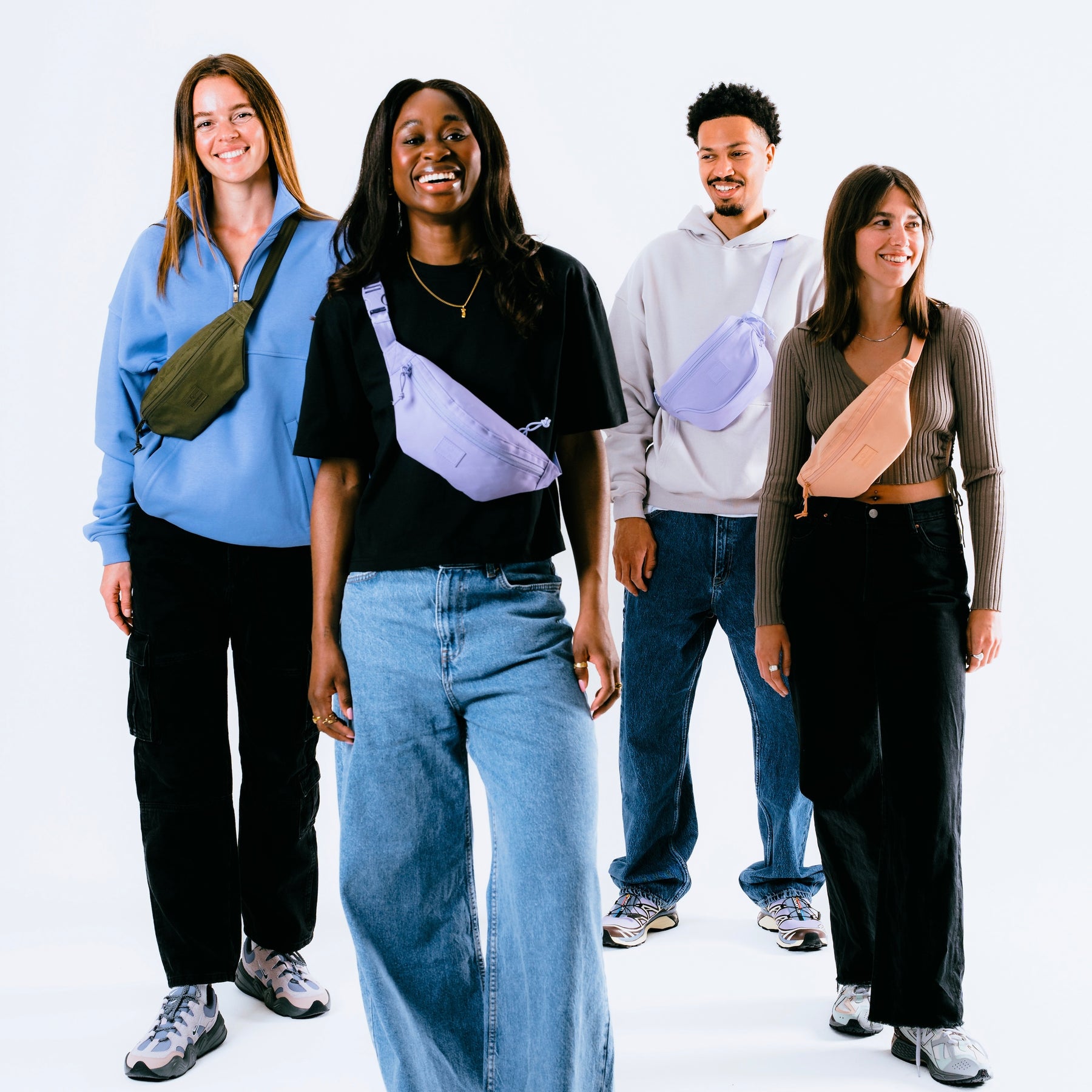 Vier Personen tragen Bauchtaschen, darunter eine peachfarbene Bauchtasche "Erik Small"