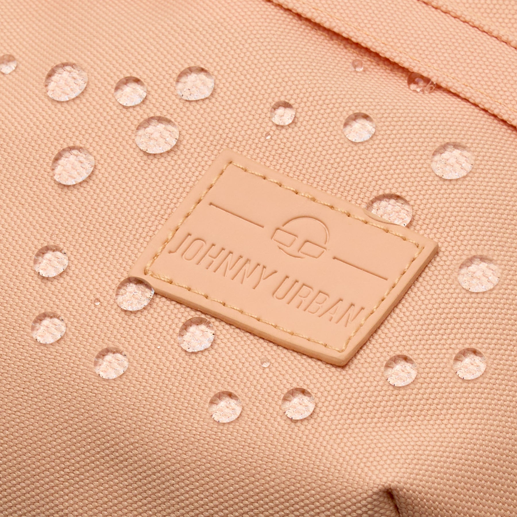 Nahaufnahme der wasserabweisenden, pfirsichfarbenen Bauchtasche 'Tom' mit aufgenähtem Johnny Urban Logo