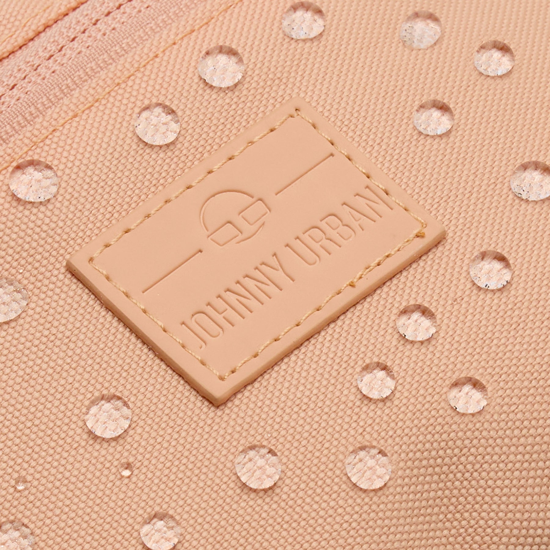 Nahaufnahme des wasserabweisenden Johnny Urban Bauchtasche Erik Small in Pfirsich mit sichtbaren Wassertropfen auf dem Stoff