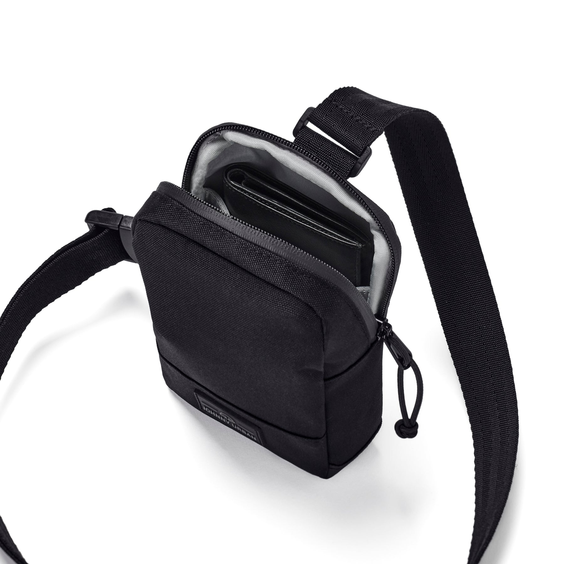 Schwarze Brusttasche 'Arthur' von Johnny Urban mit Reißverschluss geöffnet, darin ein Portemonnaie