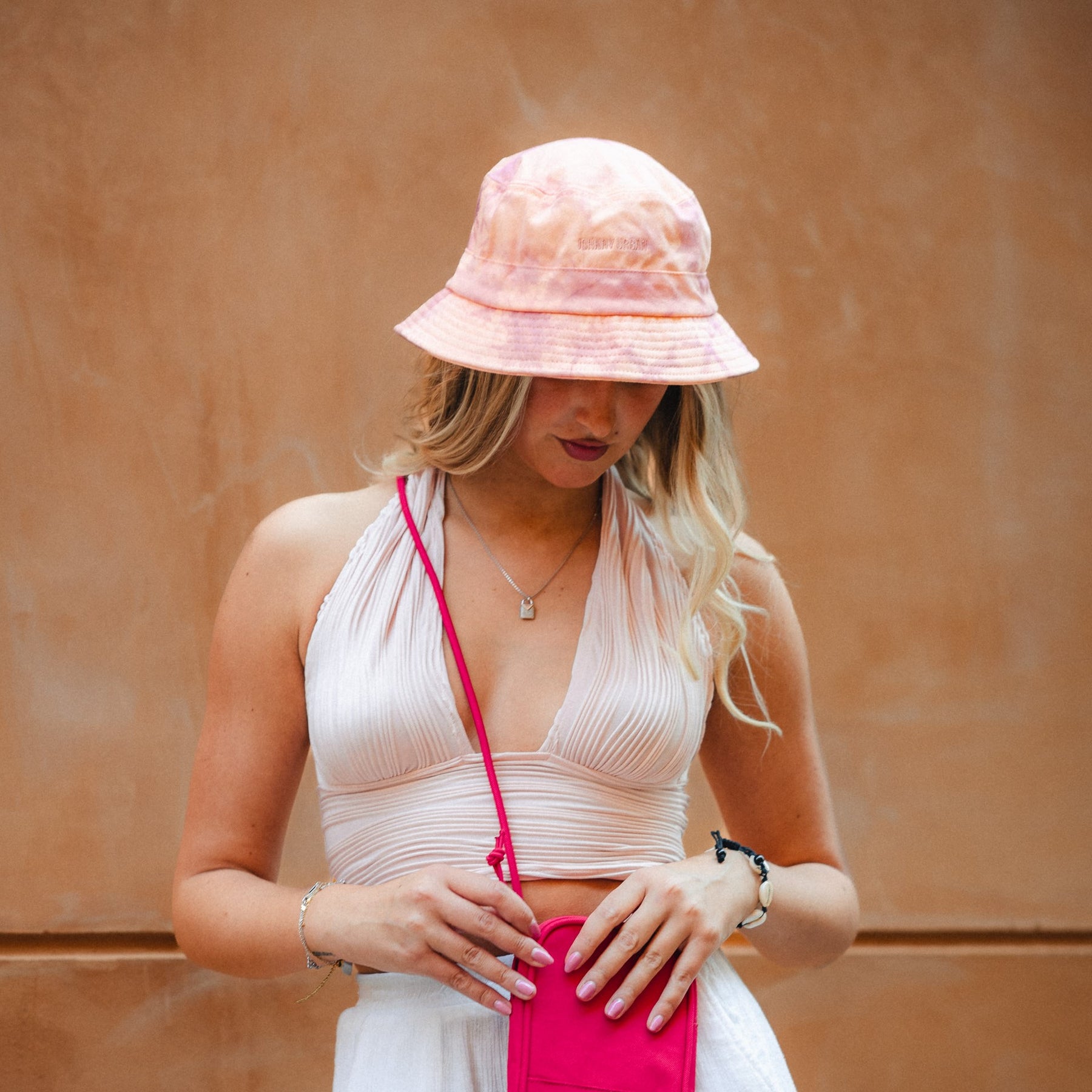 Frau mit hellrosa Batik-Bucket-Hat 'Gill', krempelbarem Saum und Johnny Urban Logo