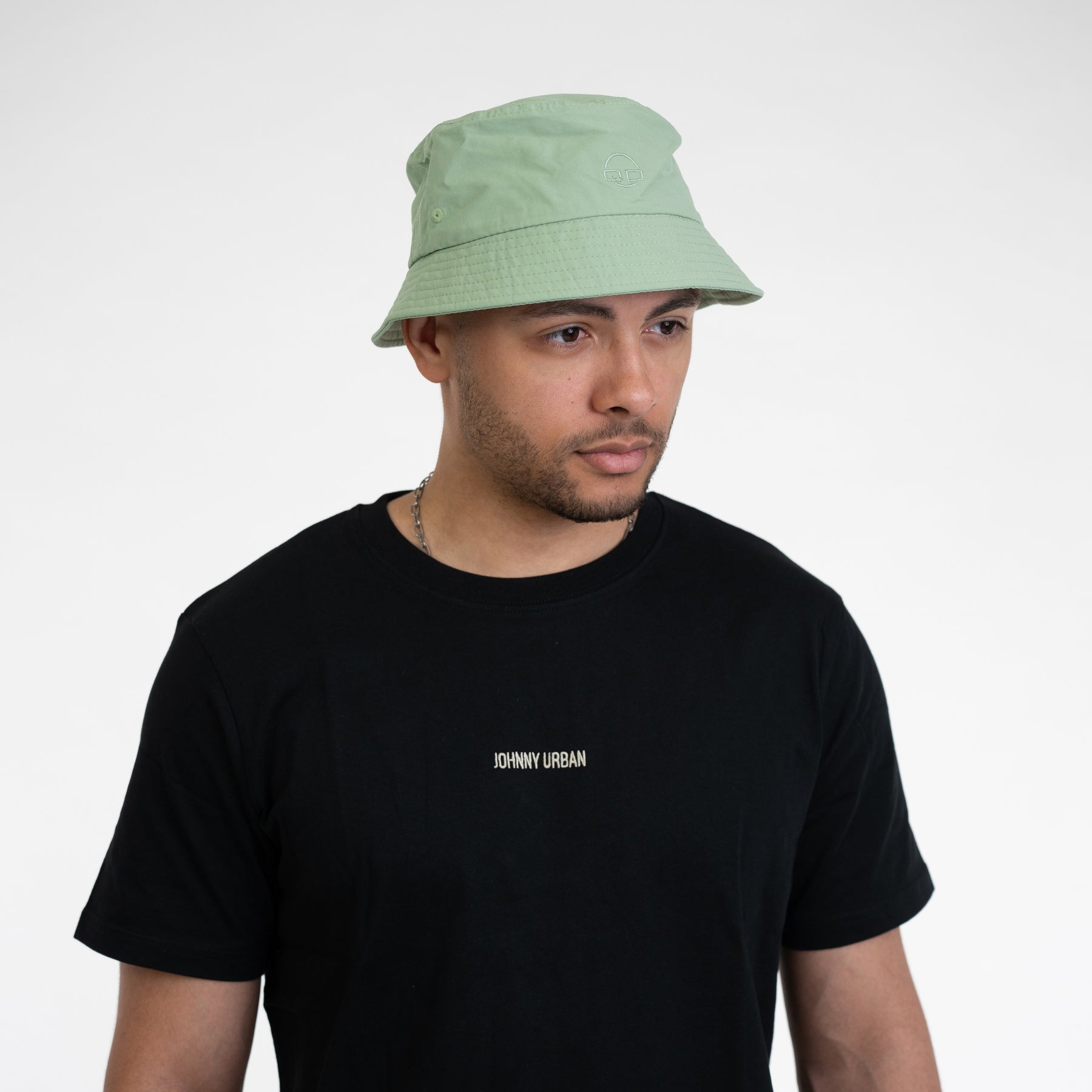 Mann trägt sage-grünen Bucket Hat 'Bob' von Johnny Urban und schwarzes T-Shirt mit kleinem Logo