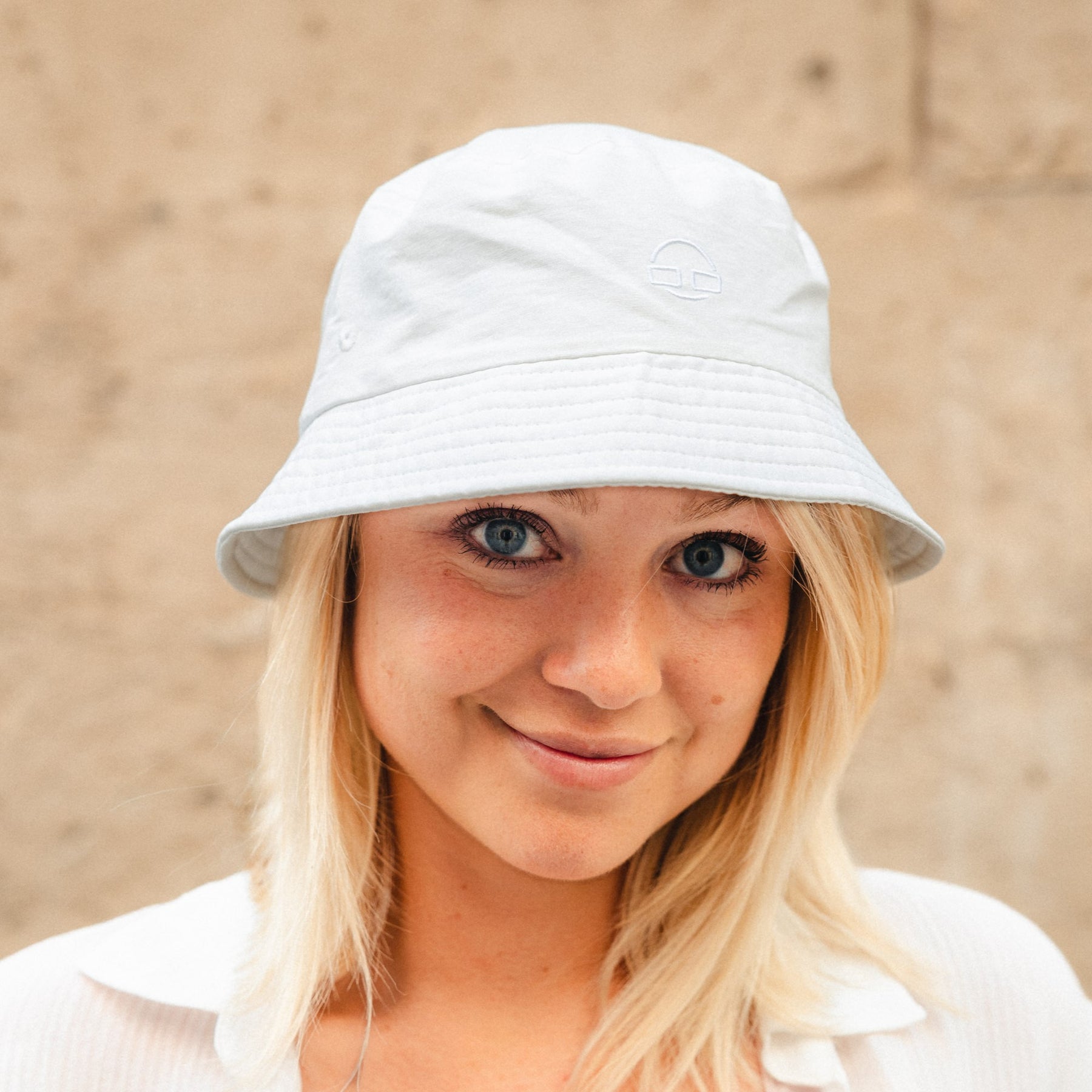 Frau mit weißem Bucket Hat 'Bob' von Johnny Urban vor beigem Hintergrund