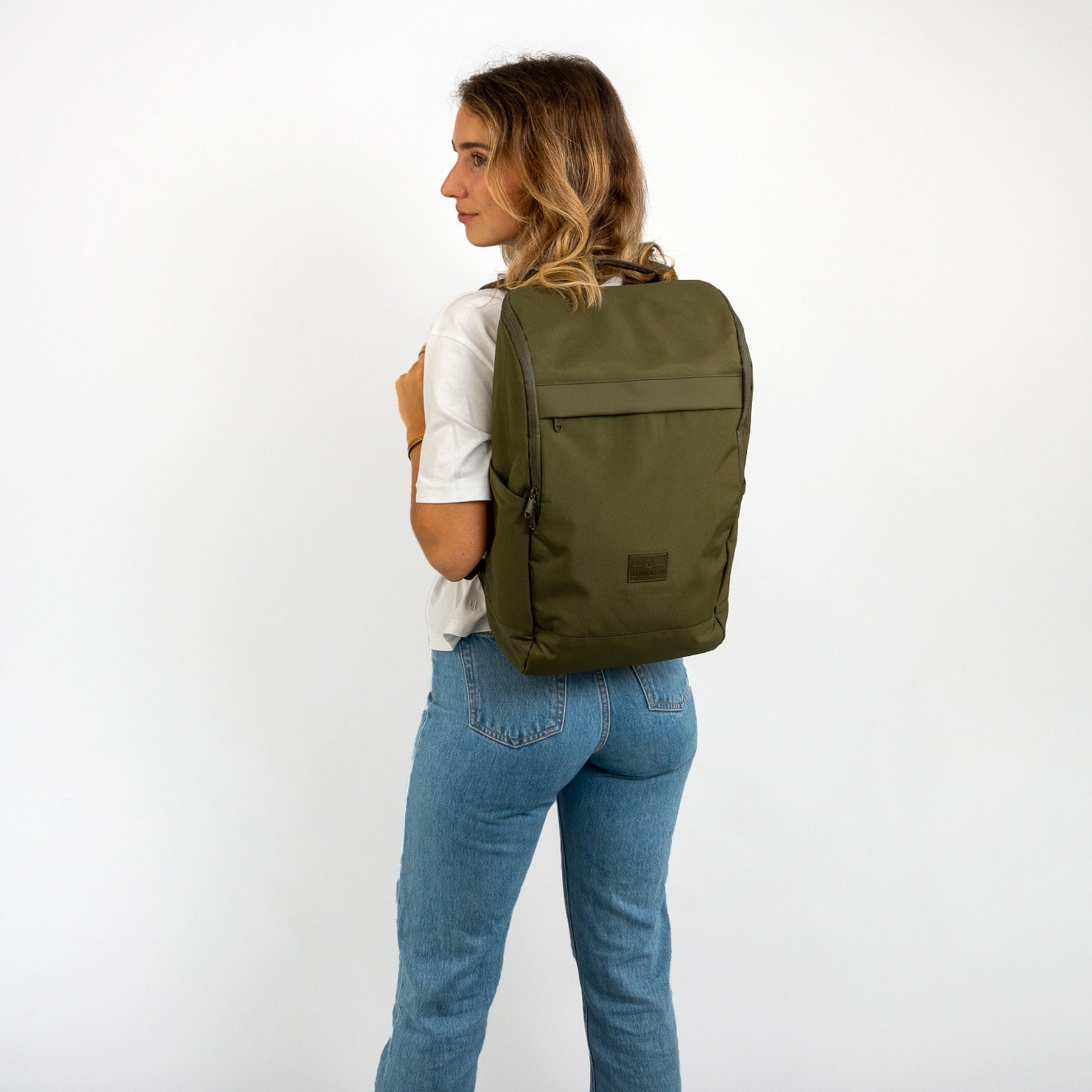 Frau trägt olivgrünen Business-Rucksack 'Jasper' von Johnny Urban, weißes T-Shirt, blaue Jeans