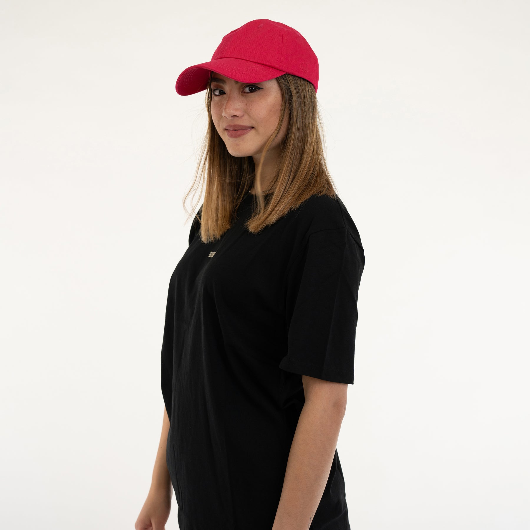 Frau trägt pinke Canvas-Cap 'Jen' und schwarzes T-Shirt, seitliche Ansicht
