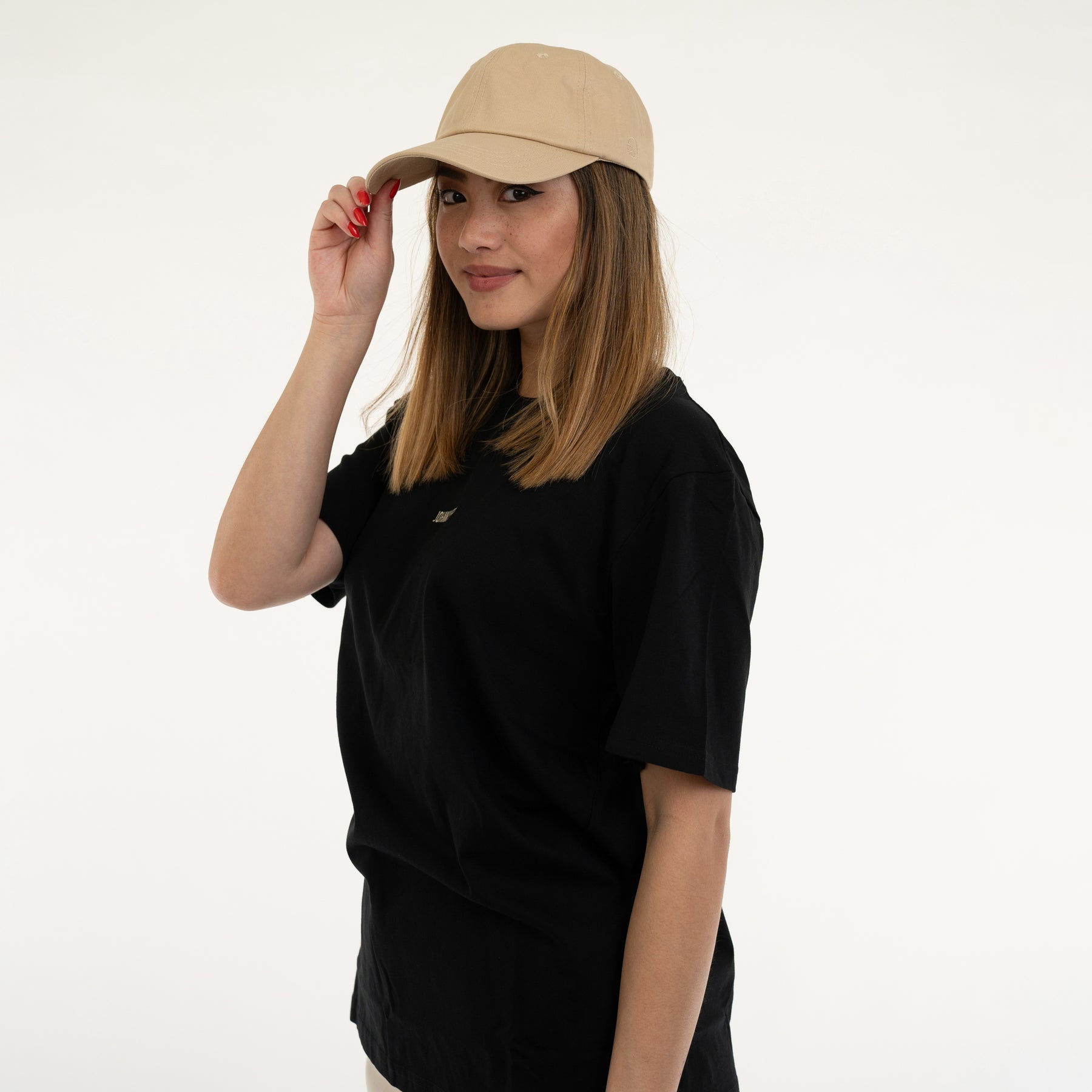 Frau mit mittellangen braunen Haaren trägt die sandfarbene Damen-Cap 'Jen' von Johnny Urban und ein schwarzes T-Shirt