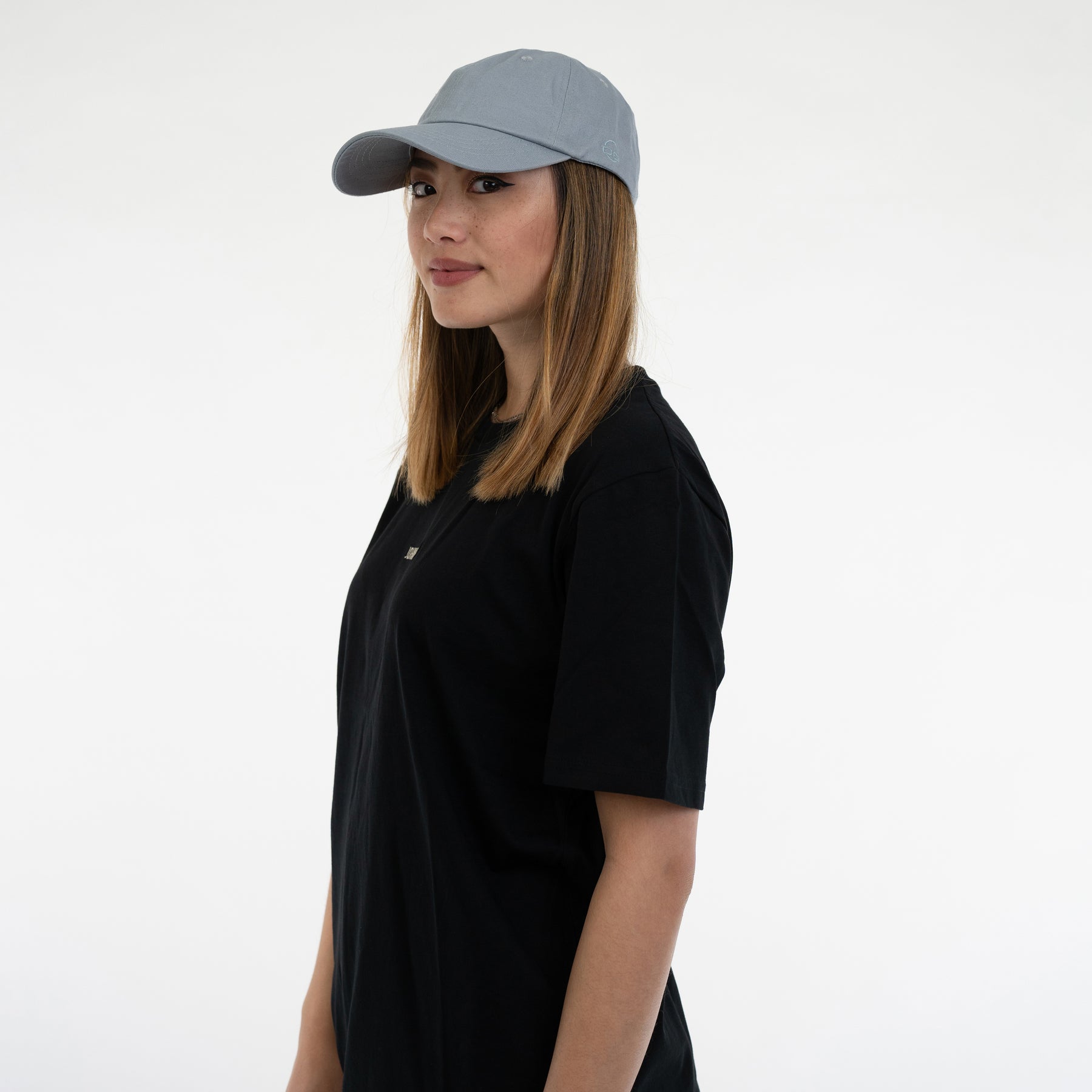 Seitliches Porträt einer Frau mit blaugrauer Cap 'Jen' von Johnny Urban und schwarzem T-Shirt