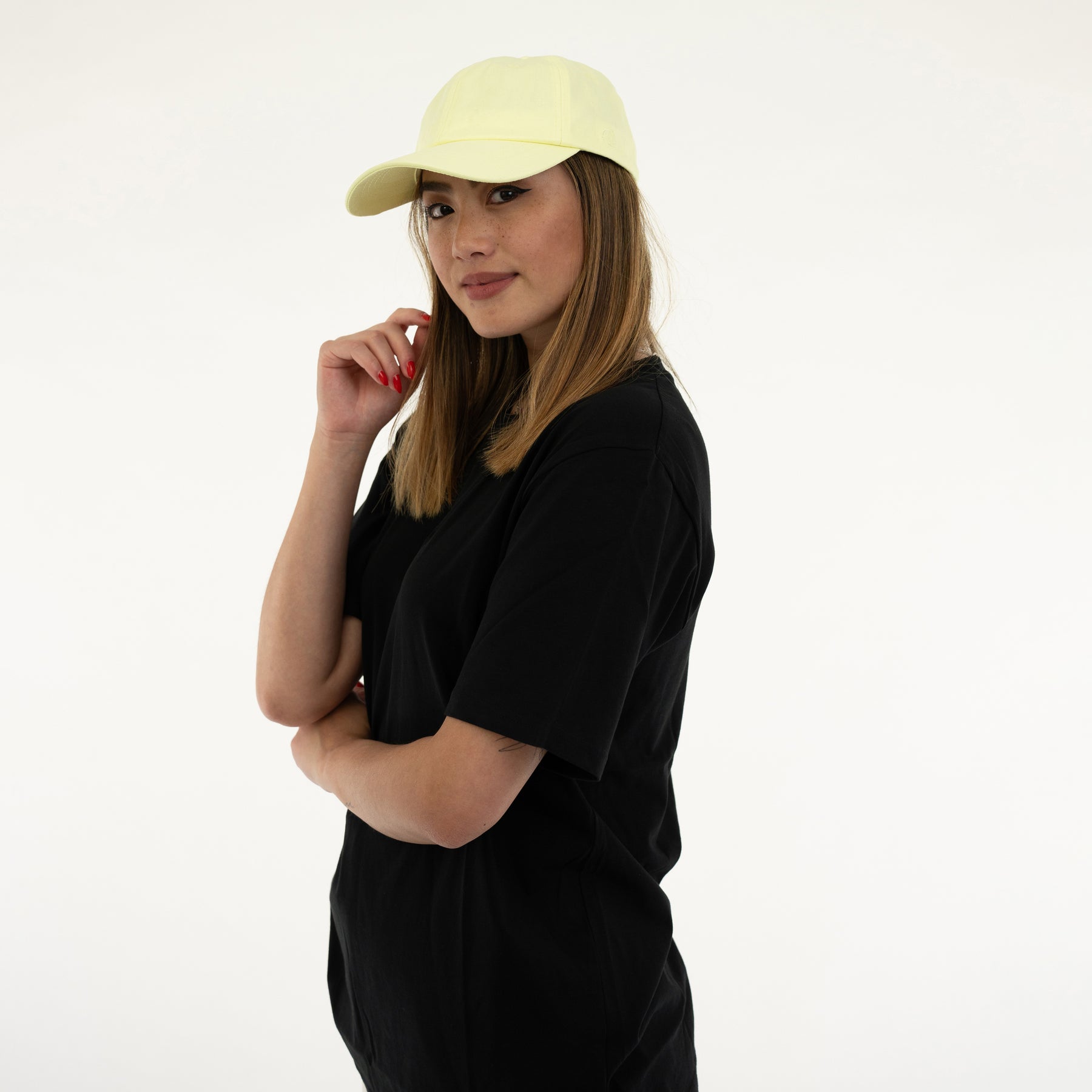 Frau mit schwarzem T-Shirt und lime-gelber Cap 'Jen' schaut zur Seite