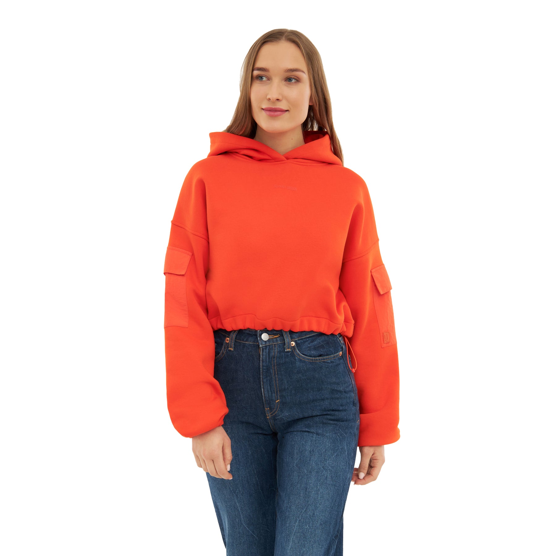 Junge Frau trägt rotes, kurzes Hoodie 'Carly' mit Taschen an den Ärmeln und blauen Jeans