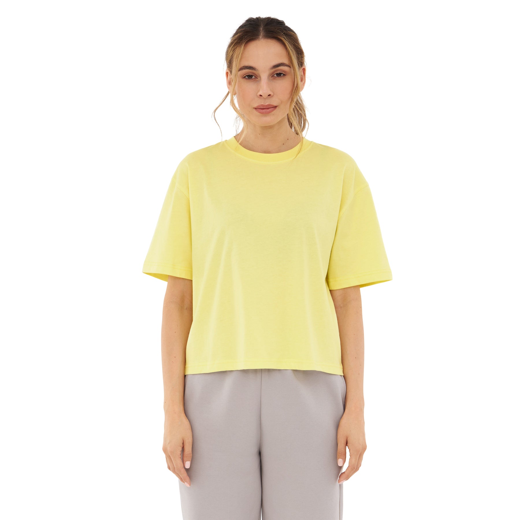 Frau trägt gelbes Cropped T-Shirt 'Zoey JU' und graue Hose, frontal stehend