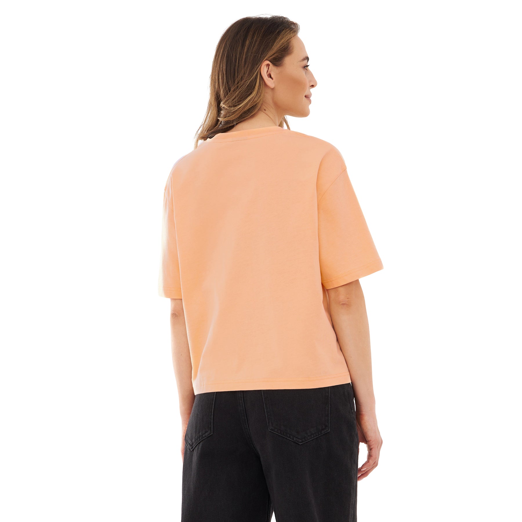 Rückansicht einer Frau mit peachfarbenem, oversized Cropped T-Shirt 'Zoey' und schwarzen Jeans
