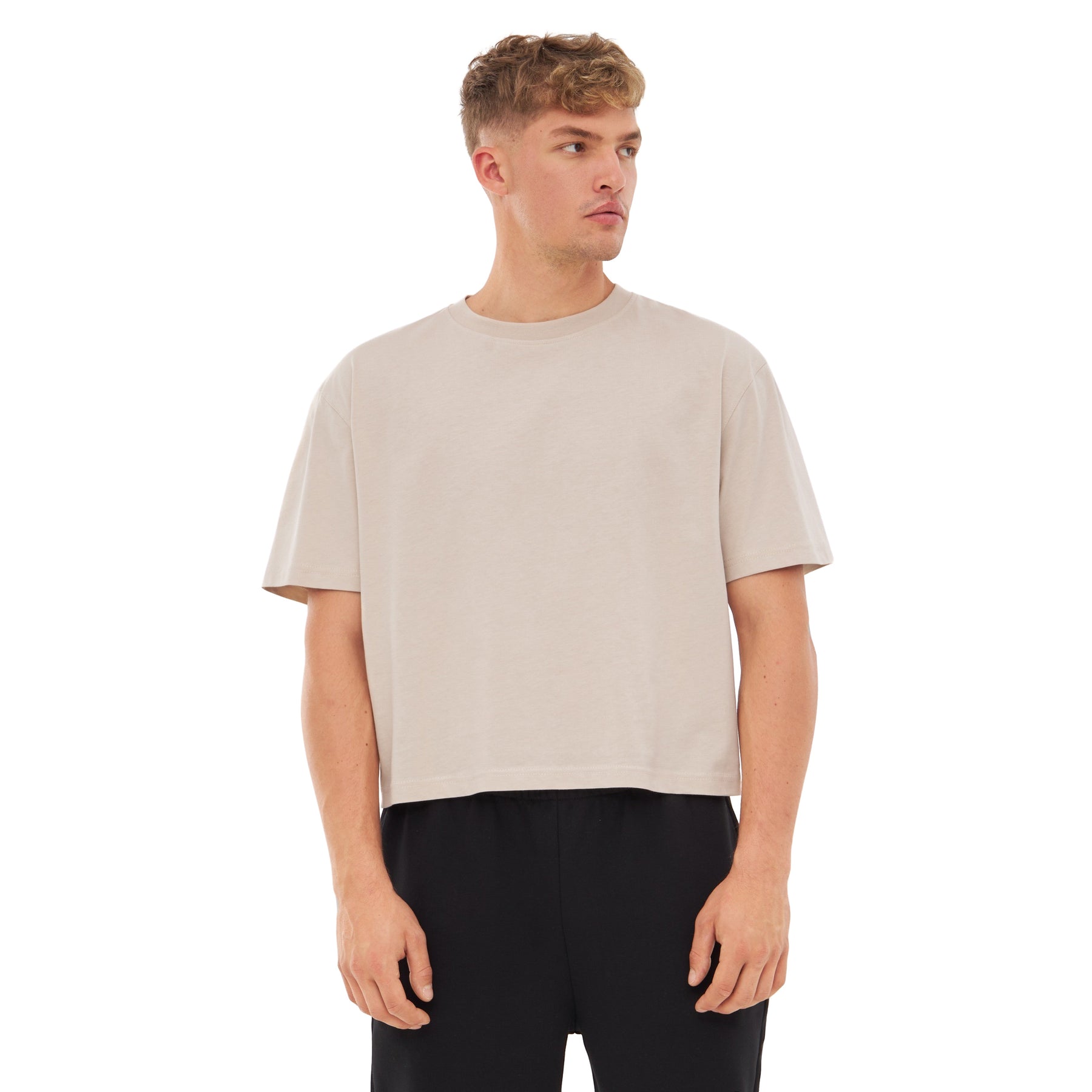 Mann trägt beige Cropped T-Shirt 'Zoey' mit kurzen Ärmeln und schwarzen Hosen