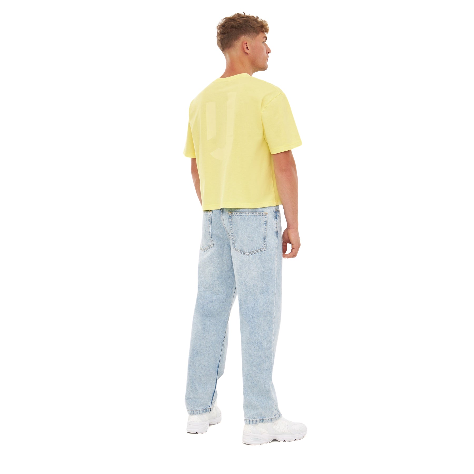 Mann trägt gelbes Cropped T-Shirt 'Zoey JU' und helle weite Jeans von hinten