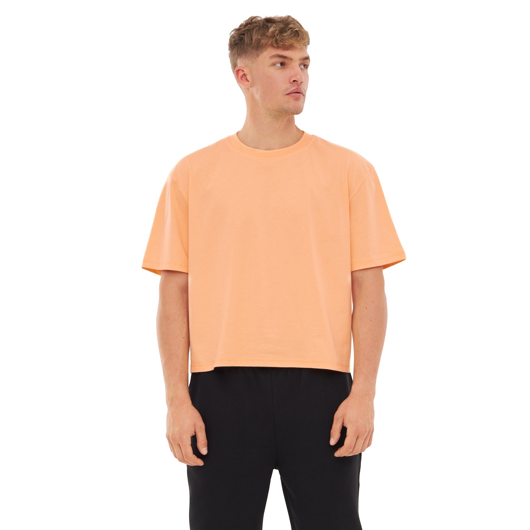 Mann trägt Cropped T-Shirt 'Zoey' in Pfirsichfarbe mit kurzen Ärmeln und rundem Ausschnitt