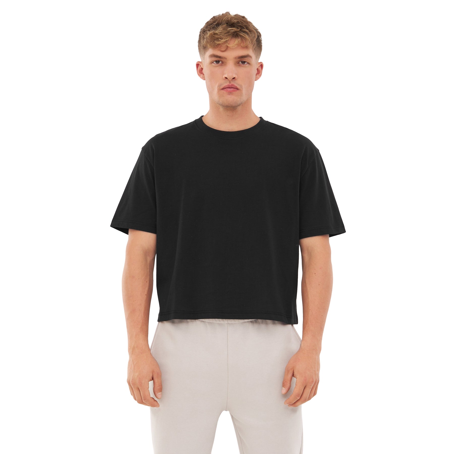 Mann trägt schwarzes Cropped T-Shirt 'Zoey' und helle Hose
