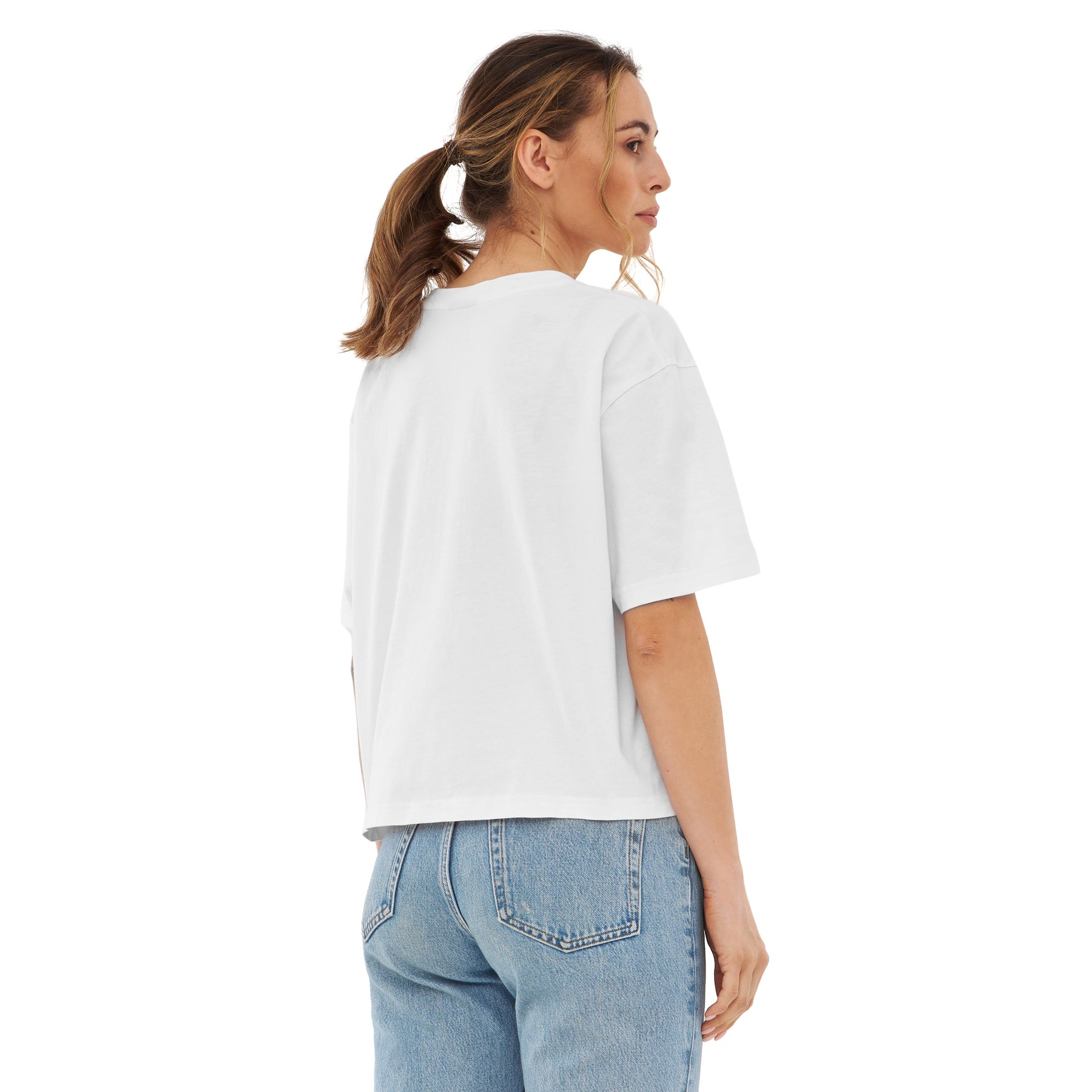 Frau trägt weiße oversized Cropped T-Shirt 'Zoey' und blaue Jeans, Rückansicht