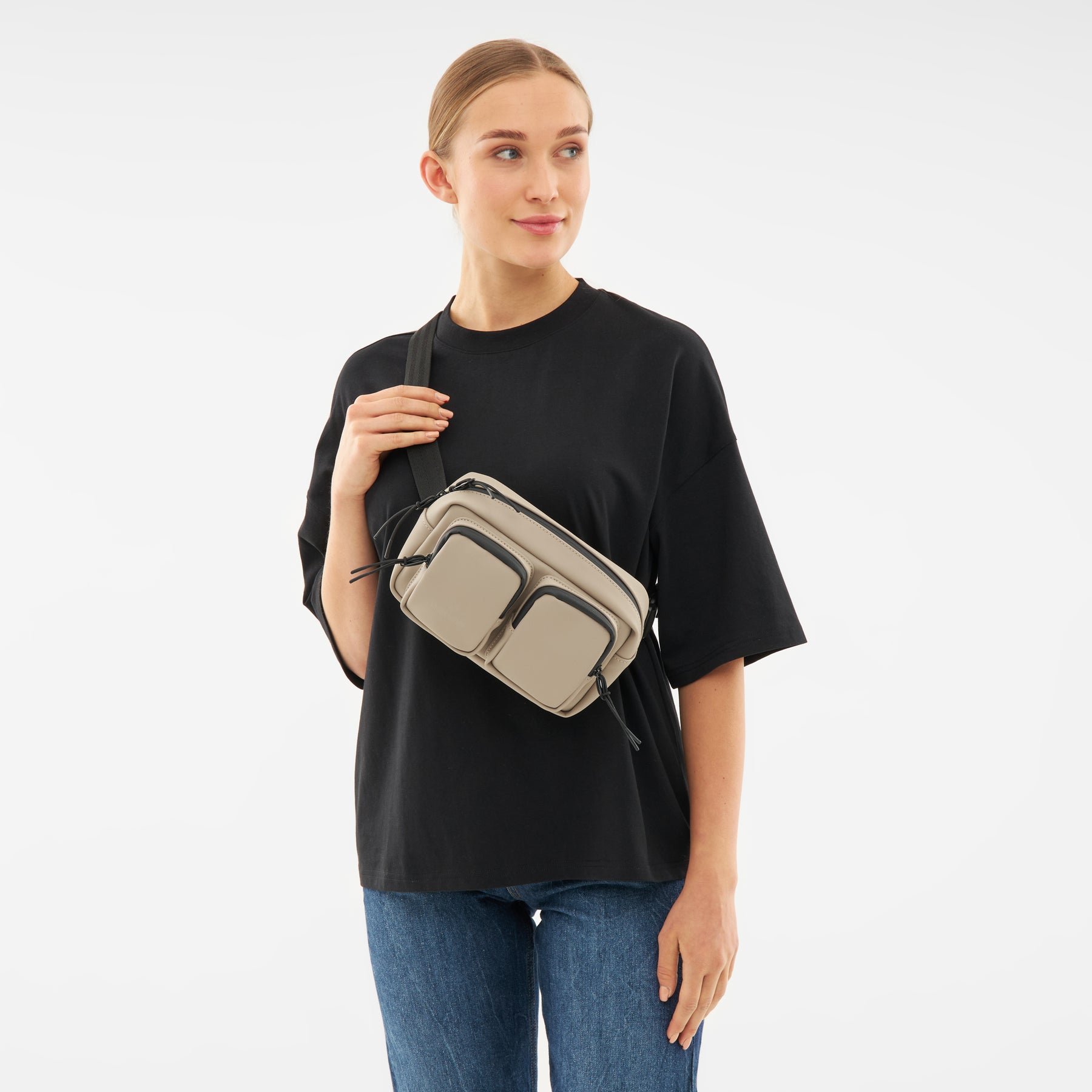 Frau trägt beige Umhängetasche 'Wesley' von Johnny Urban über schwarzem T-Shirt und blauen Jeans