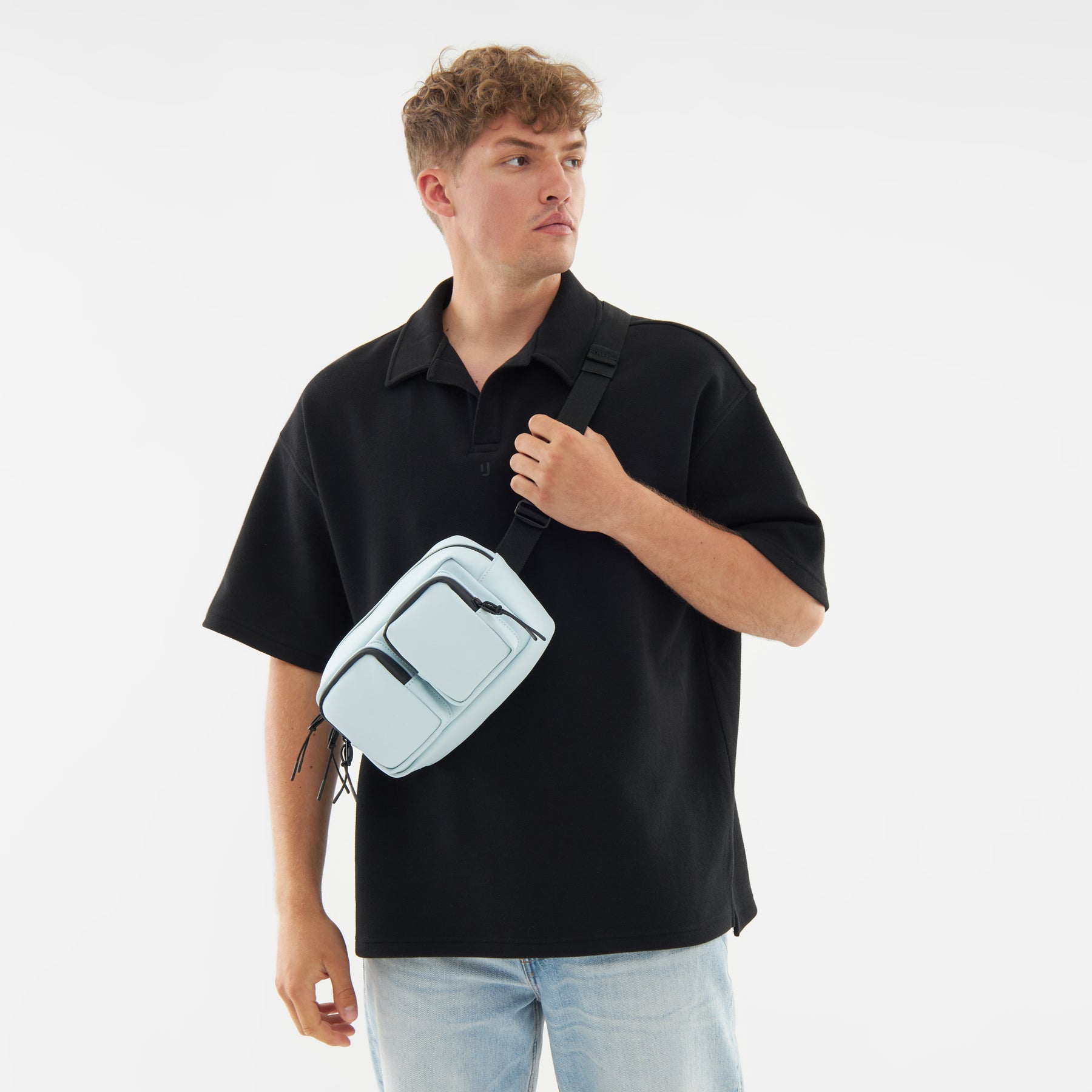 Mann mit schwarzem Poloshirt und hellblauer Umhängetasche 'Wesley' von Johnny Urban