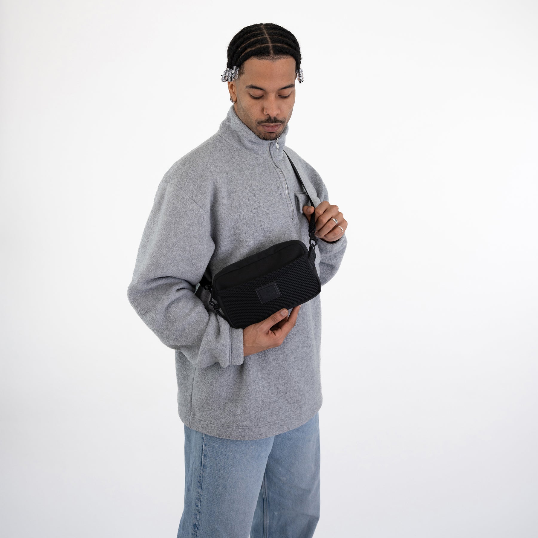 Mann trägt schwarze Johnny Urban Umhängetasche 'Elliot' über grauem Pullover und blauen Jeans