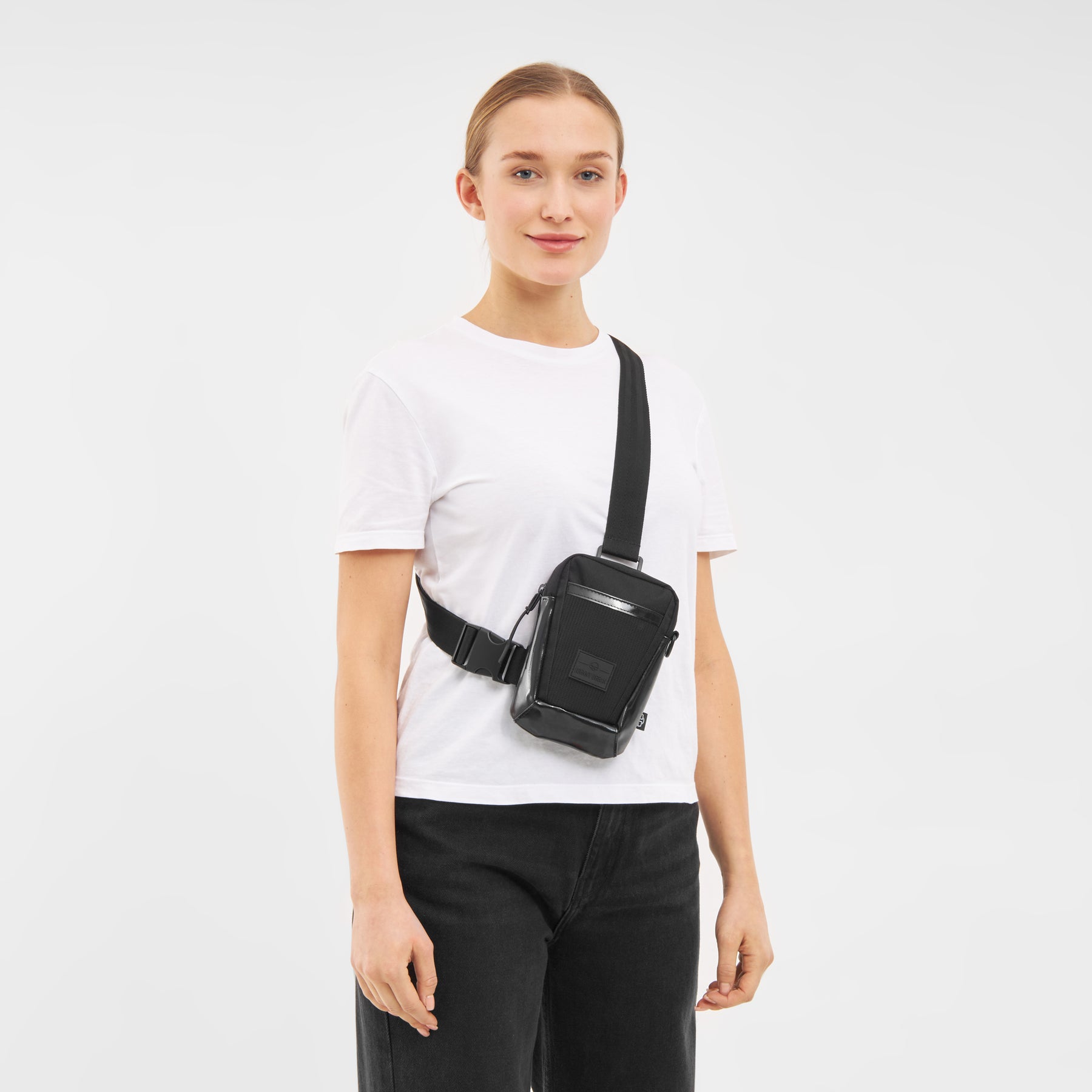 Frau trägt schwarze Umhängetasche 'Lex' von Johnny Urban über weißem T-Shirt und schwarzen Hosen