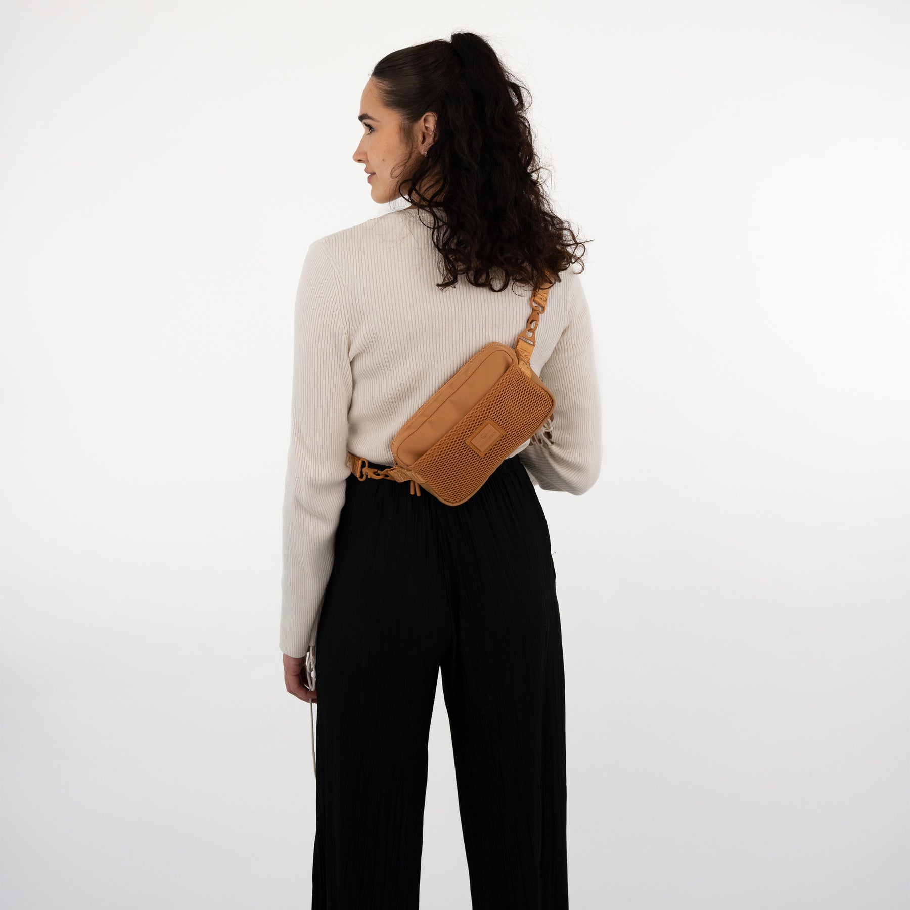 Rückansicht einer Frau mit Umhängetasche 'Elliot' in karamellfarbenem, modernem Design