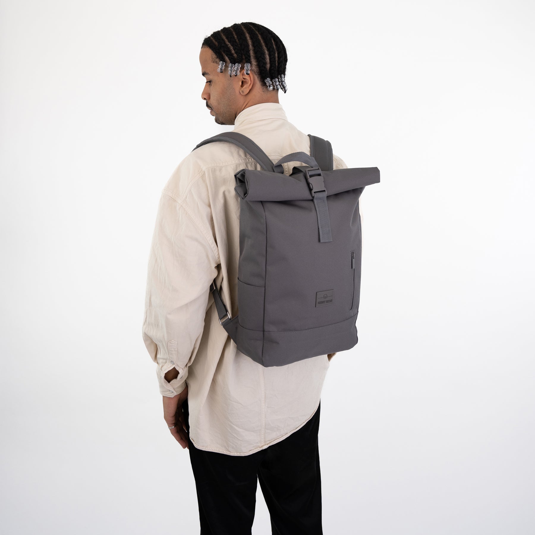 Mann von hinten mit beigem Hemd und grauem Rolltop Rucksack ‚Robin Medium‘