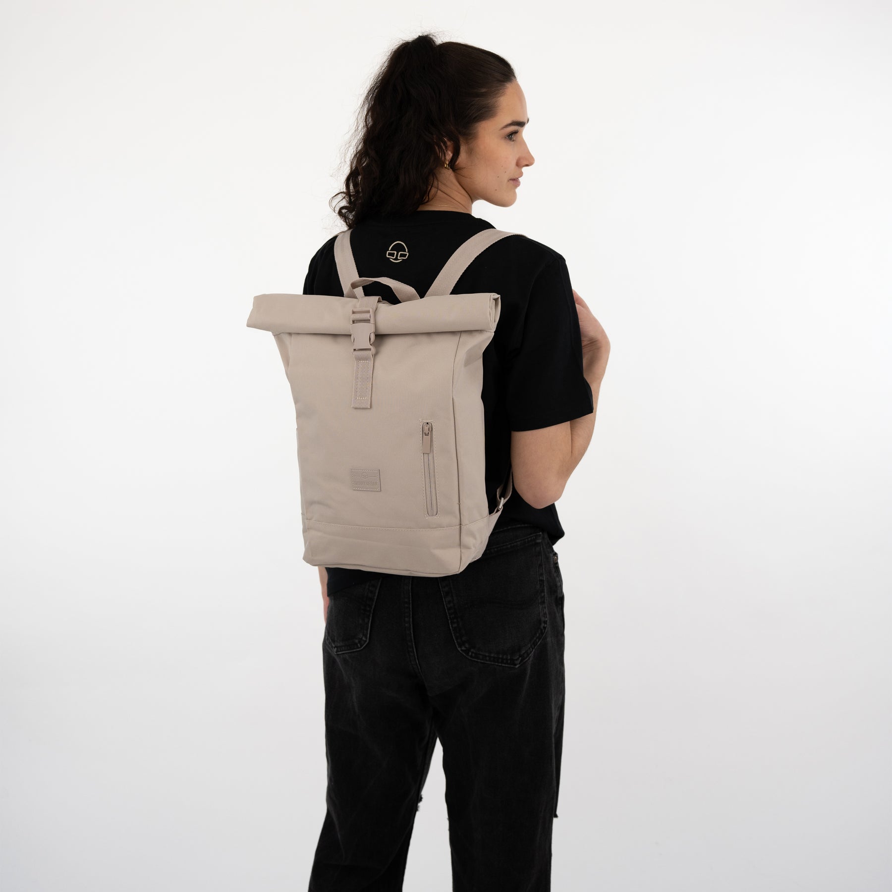 Damen-Rolltop-Rucksack 'Robin Small' in Beige getragen von Frau mit schwarzem T-Shirt und schwarzen Jeans