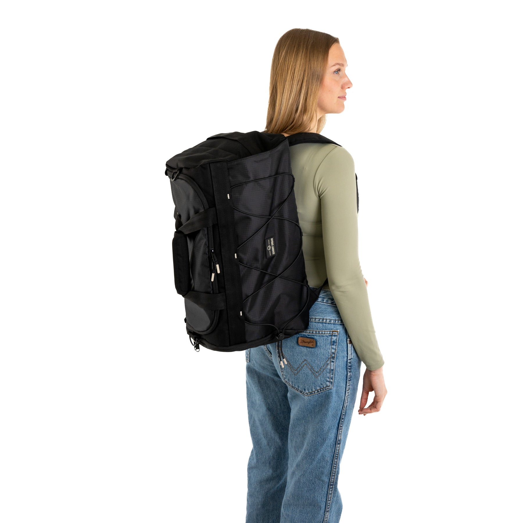 Frau trägt schwarzen Duffle Bag 'Shawn Medium' von Johnny Urban, kombiniert mit langärmeligem, olivgrünem Oberteil und Jeans