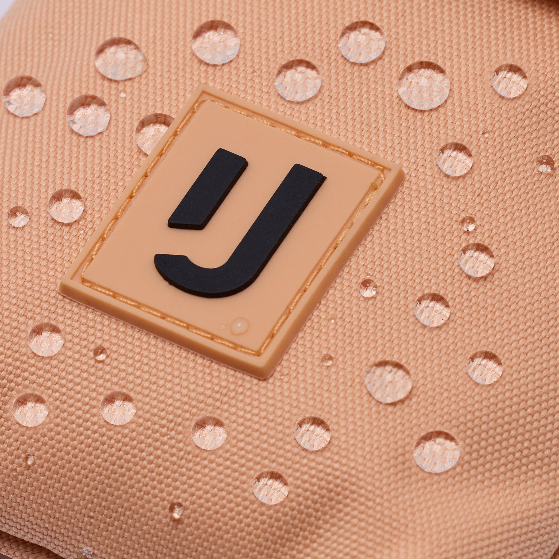 Nahaufnahme der wasserdichten Oberfläche einer 'Juno' Hals-Tasche von Johnny Urban mit dem Markenlogo
