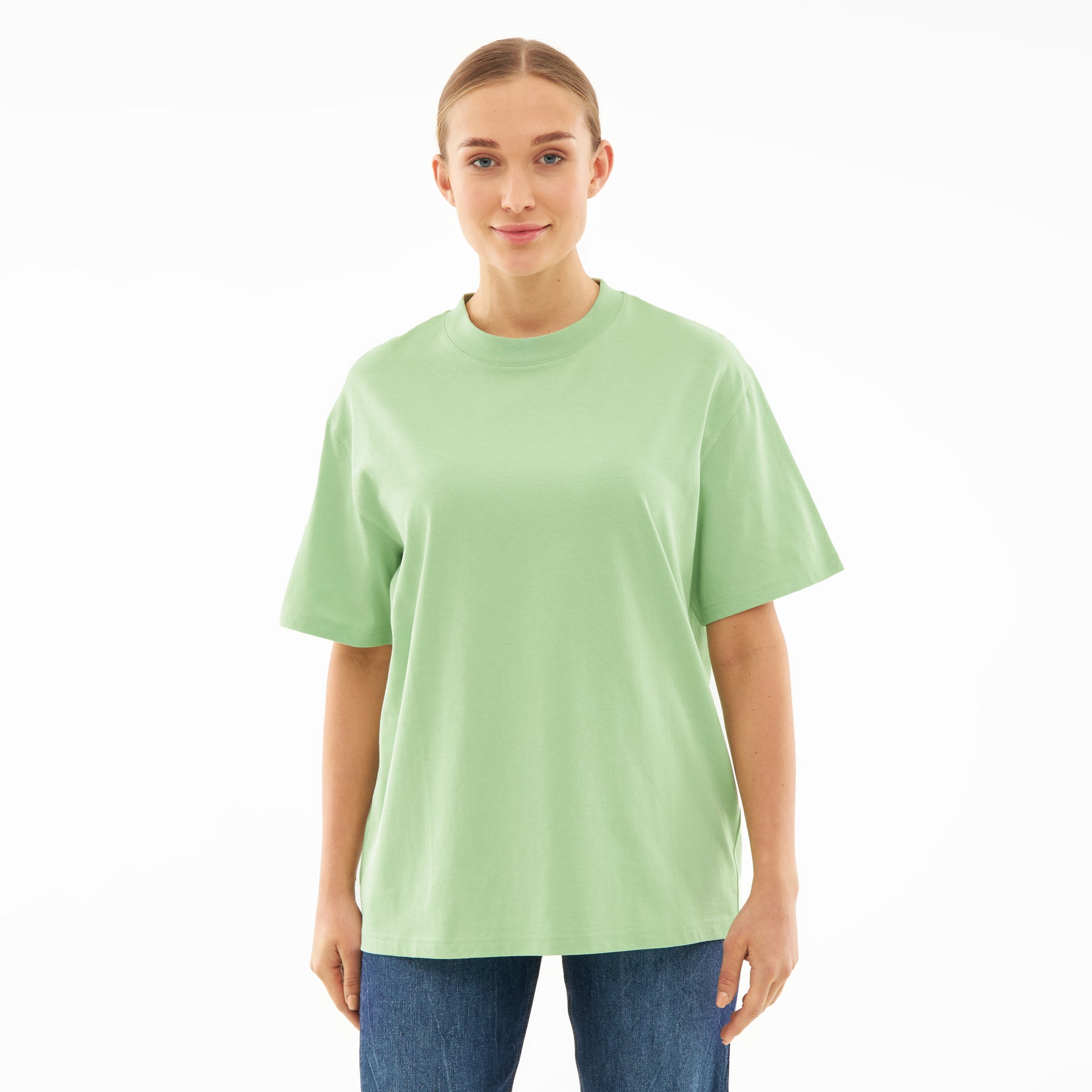 Frau trägt sage-grünes, oversized T-Shirt 'Sammy' mit Rundhalsausschnitt und blauen Jeans