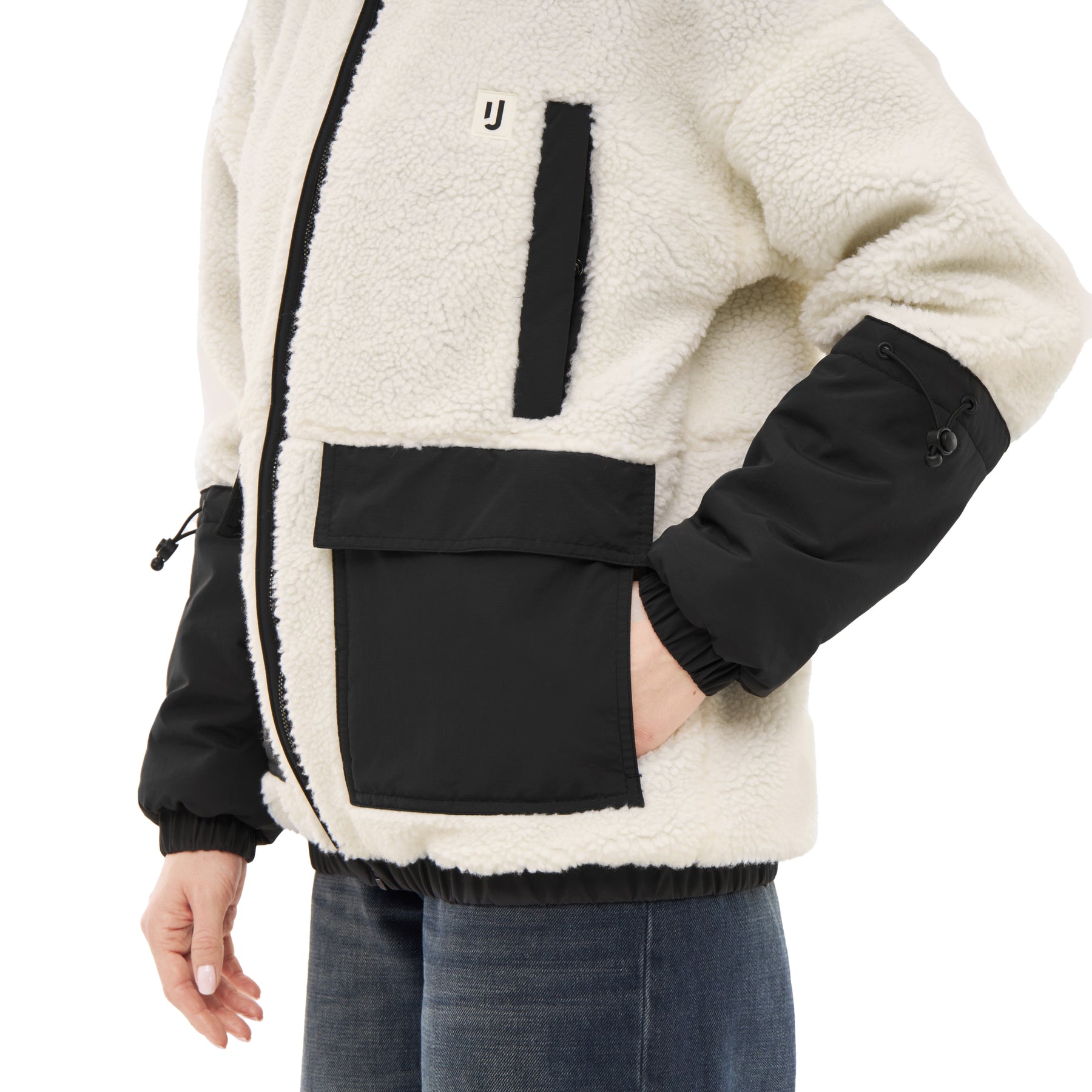 Teddy Fleecejacke 'Carson' in Creme mit schwarzen Akzenten und Taschen, an einem Mann mit Jeans