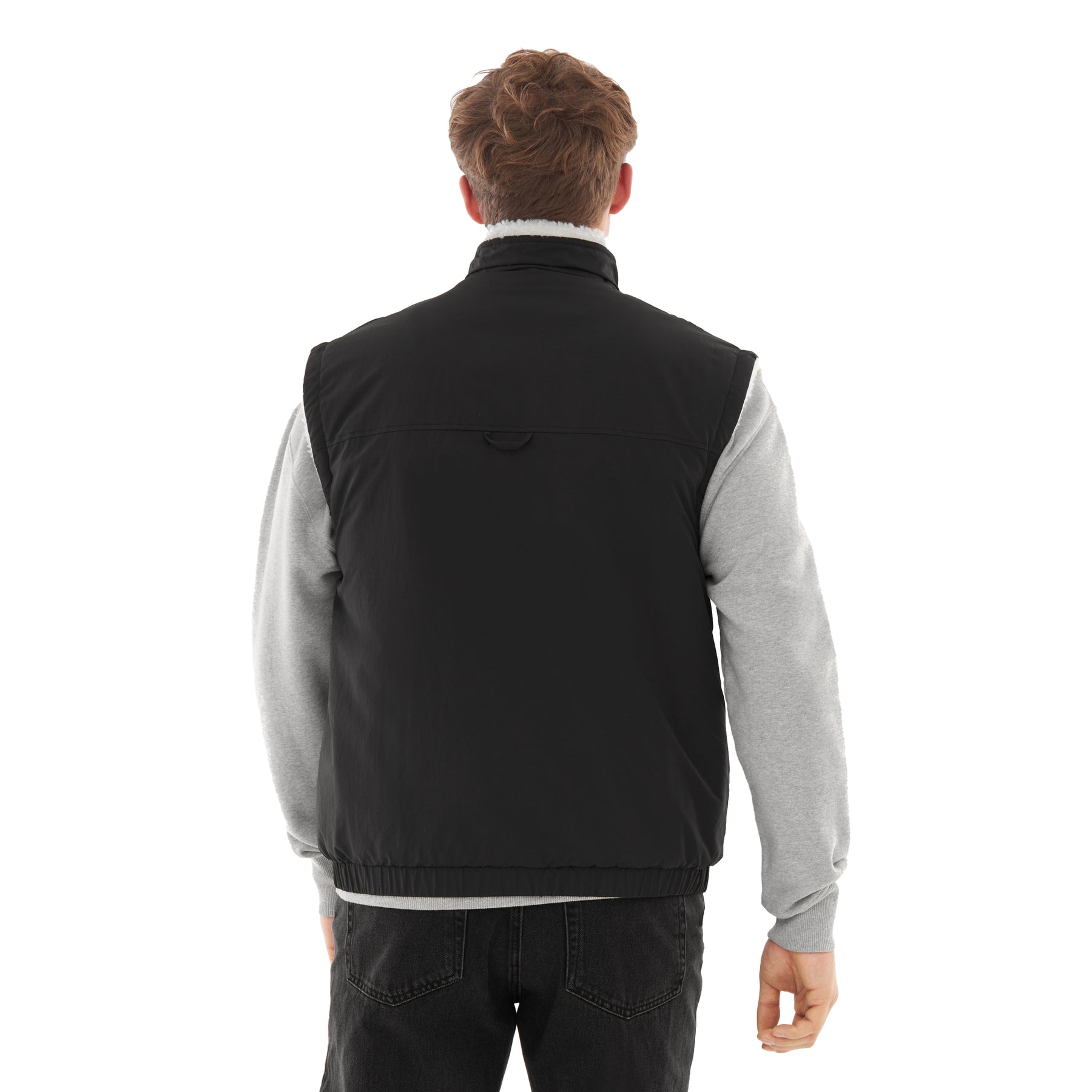 Rückansicht eines Mannes mit schwarzer Fleeceweste über grauem Pullover und schwarzen Jeans