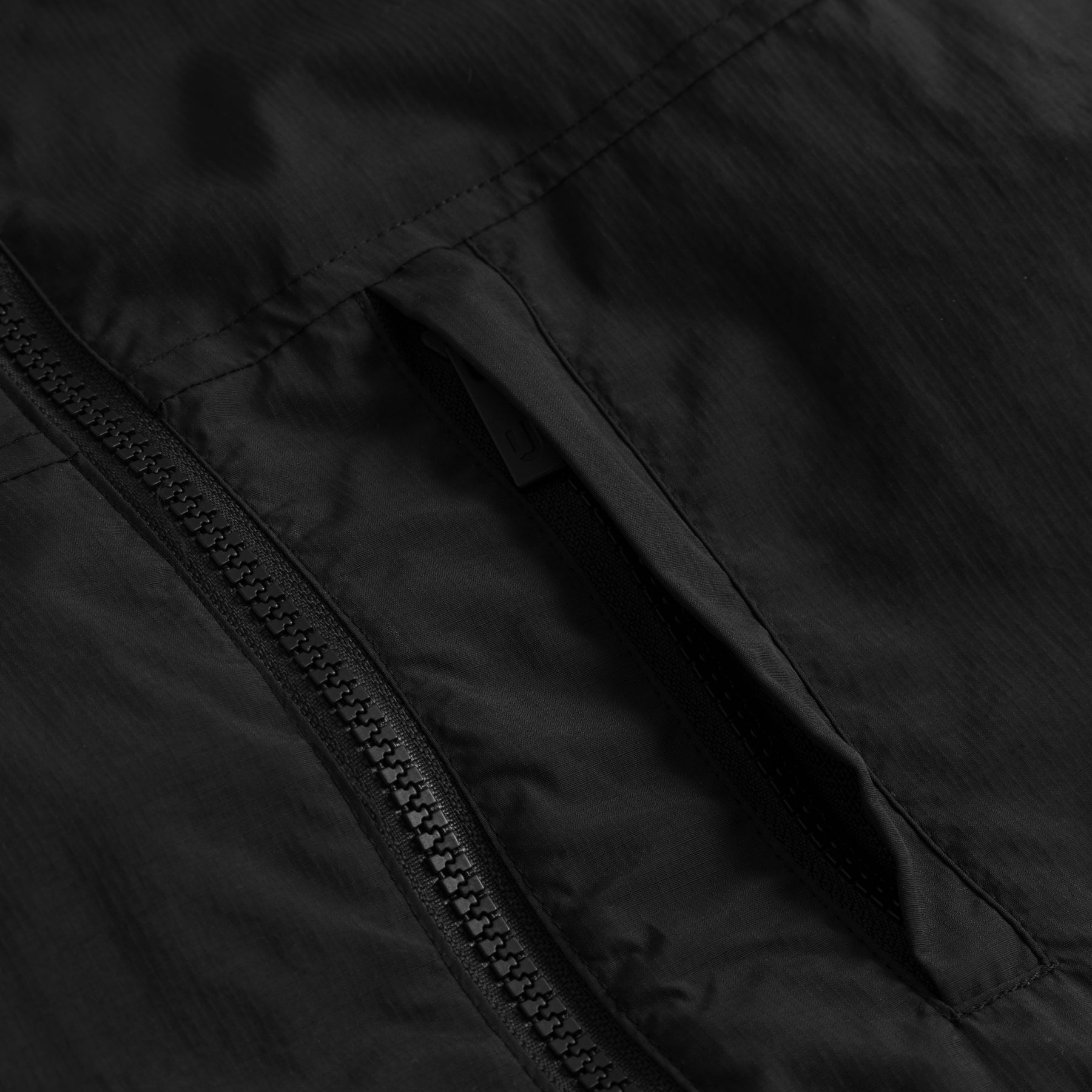 Nahe Aufnahme eines schwarzen Reißverschlusses und einer Tasche der Teddy Fleeceweste 'Bryson'