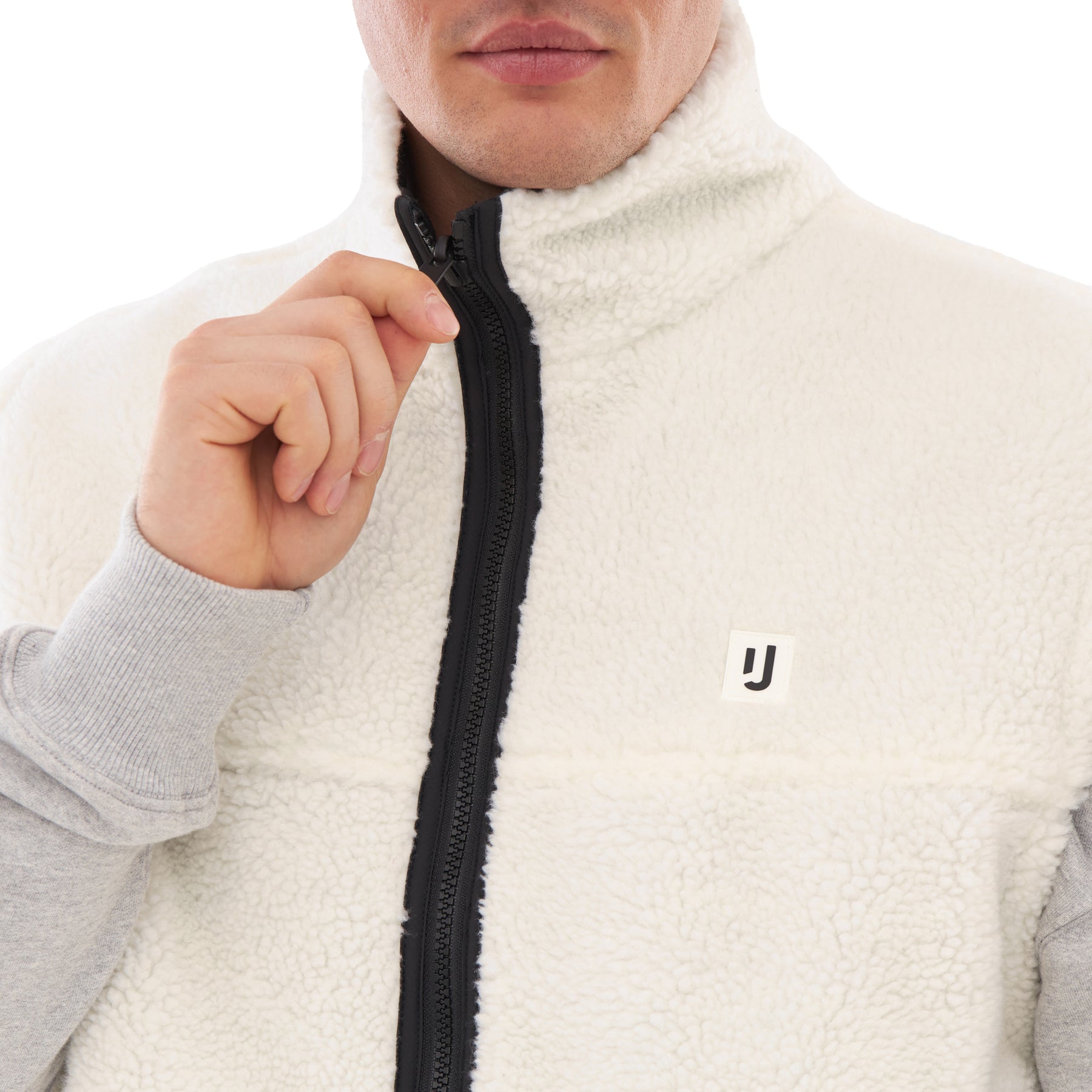 Mann zieht den Reißverschluss der cremefarbenen Teddy Fleeceweste 'Bryson' mit schwarzem Rand hoch