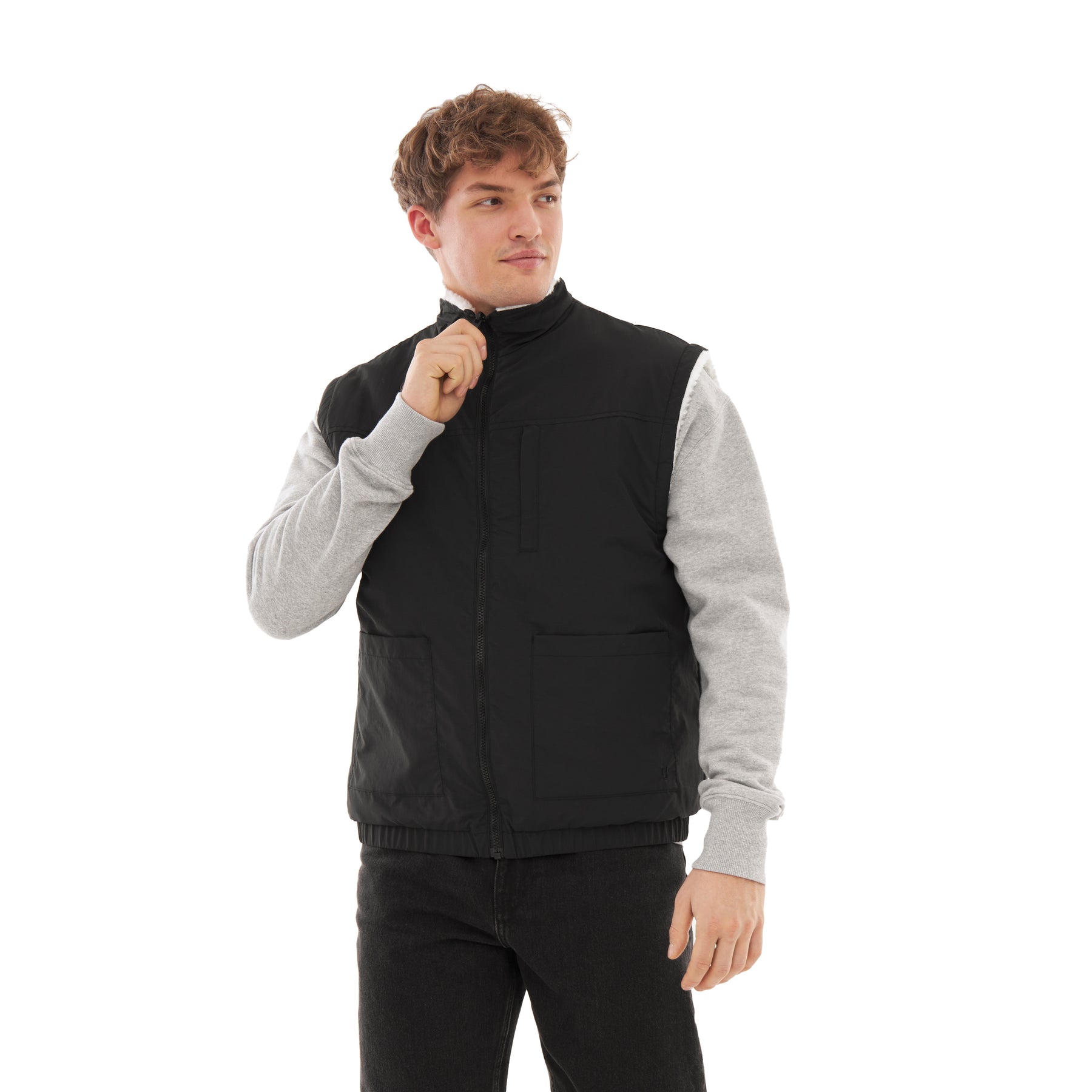 Mann trägt schwarze, wendbare Teddy Fleeceweste 'Bryson' über grauem Pullover