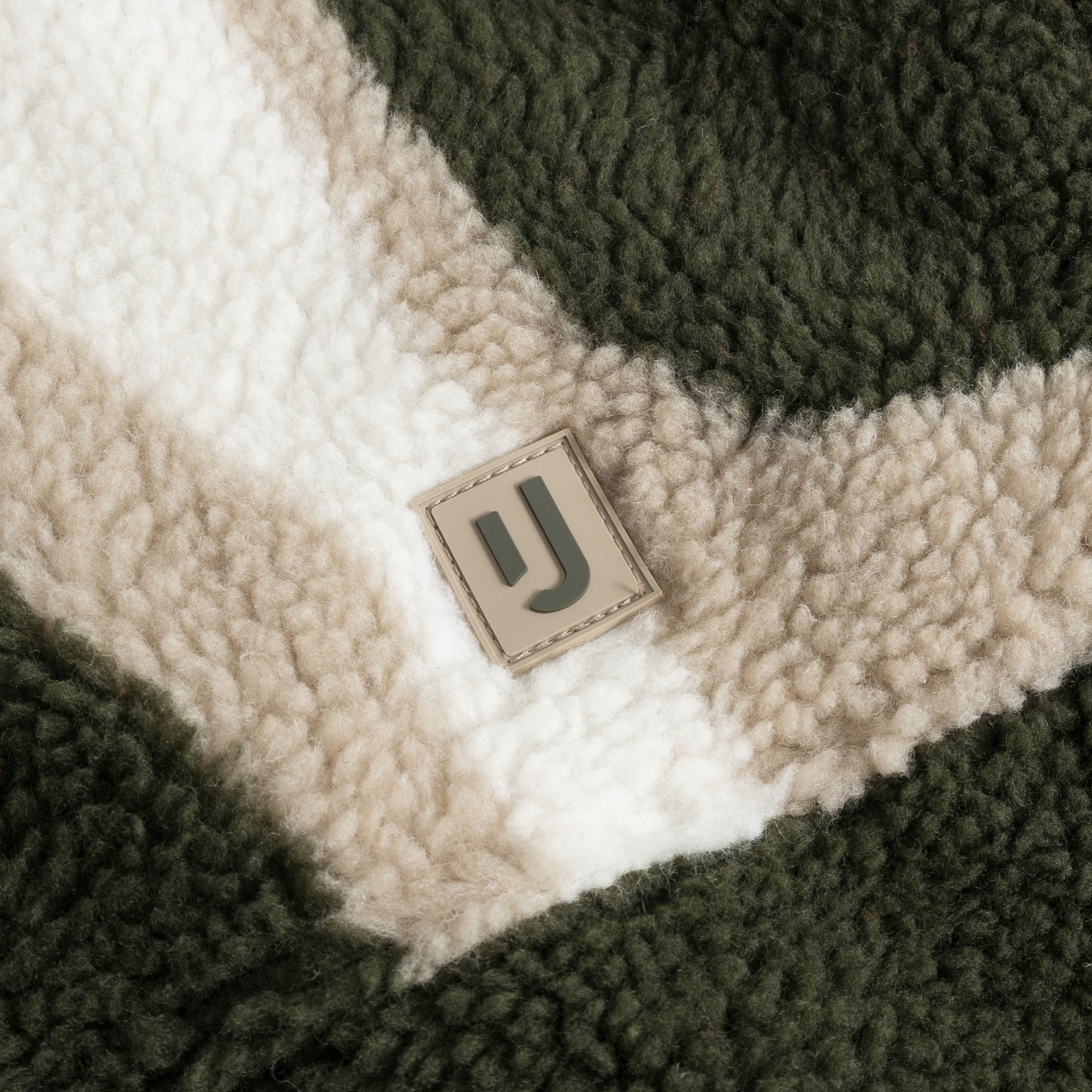 Nahaufnahme der Teddy Fleeceweste "Bryson" mit olivefarbenem und beigem Muster und Johnny Urban Logo