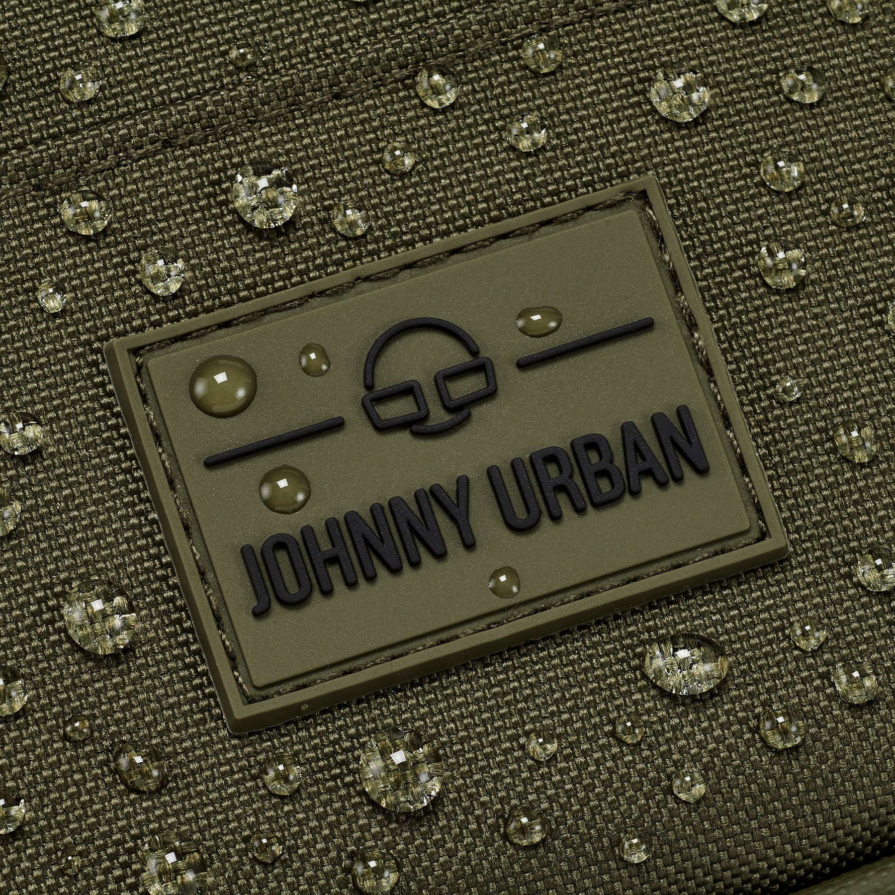 Wasserabweisender Front Pack 'Arthur' von Johnny Urban mit aufgenähtem Logo und Wassertropfen auf grünem Stoff