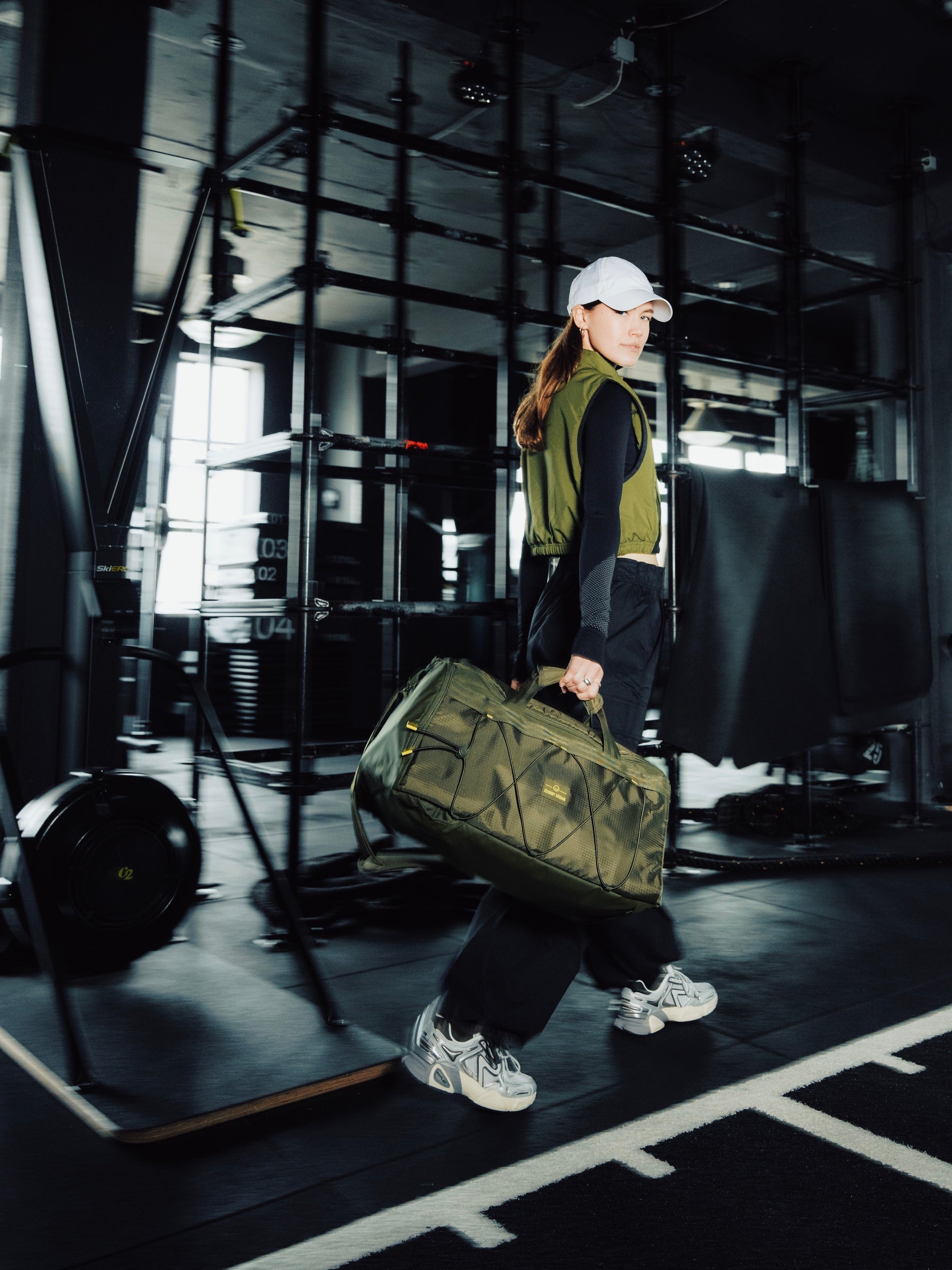 Frau ist im Fitnessstudio und läuft mit einer Sporttasche in der Hand.