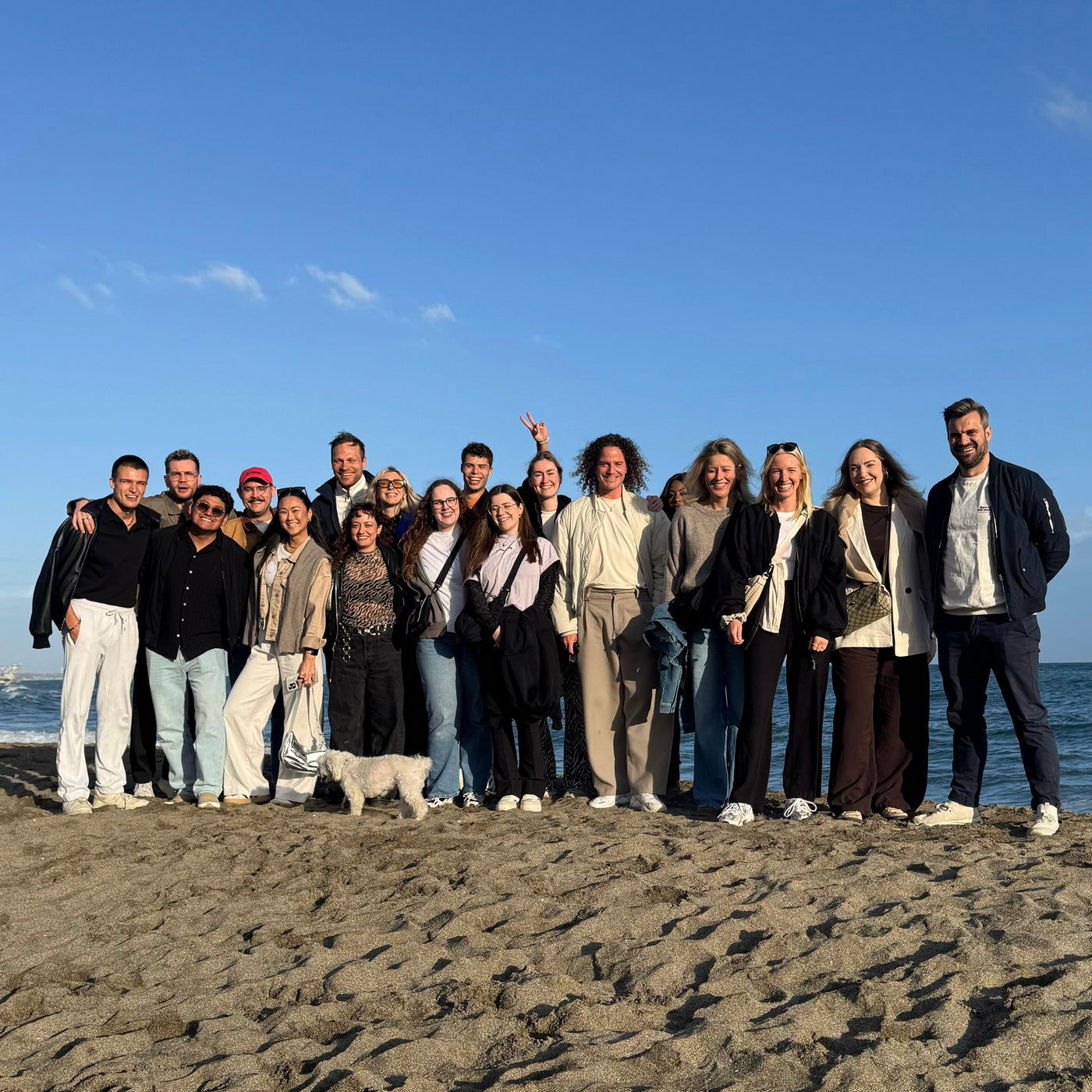 Alle Mitarbeiter von Johnny Urban stehen geschlossen am Strand bei der Workation.