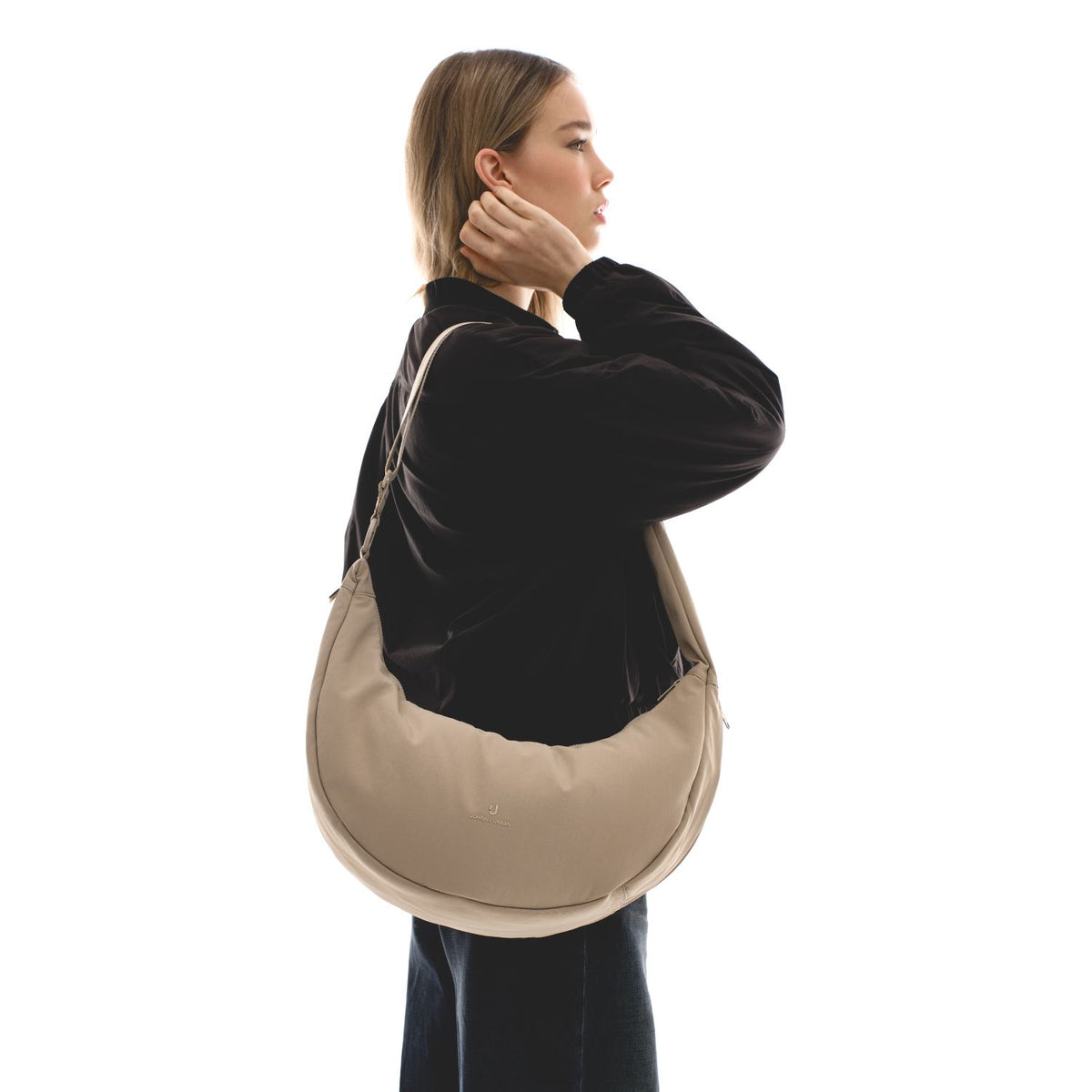 Unser weibliches Model präsentiert sich hier mit der Half-Moon-Bag "Lou Large" in beige.