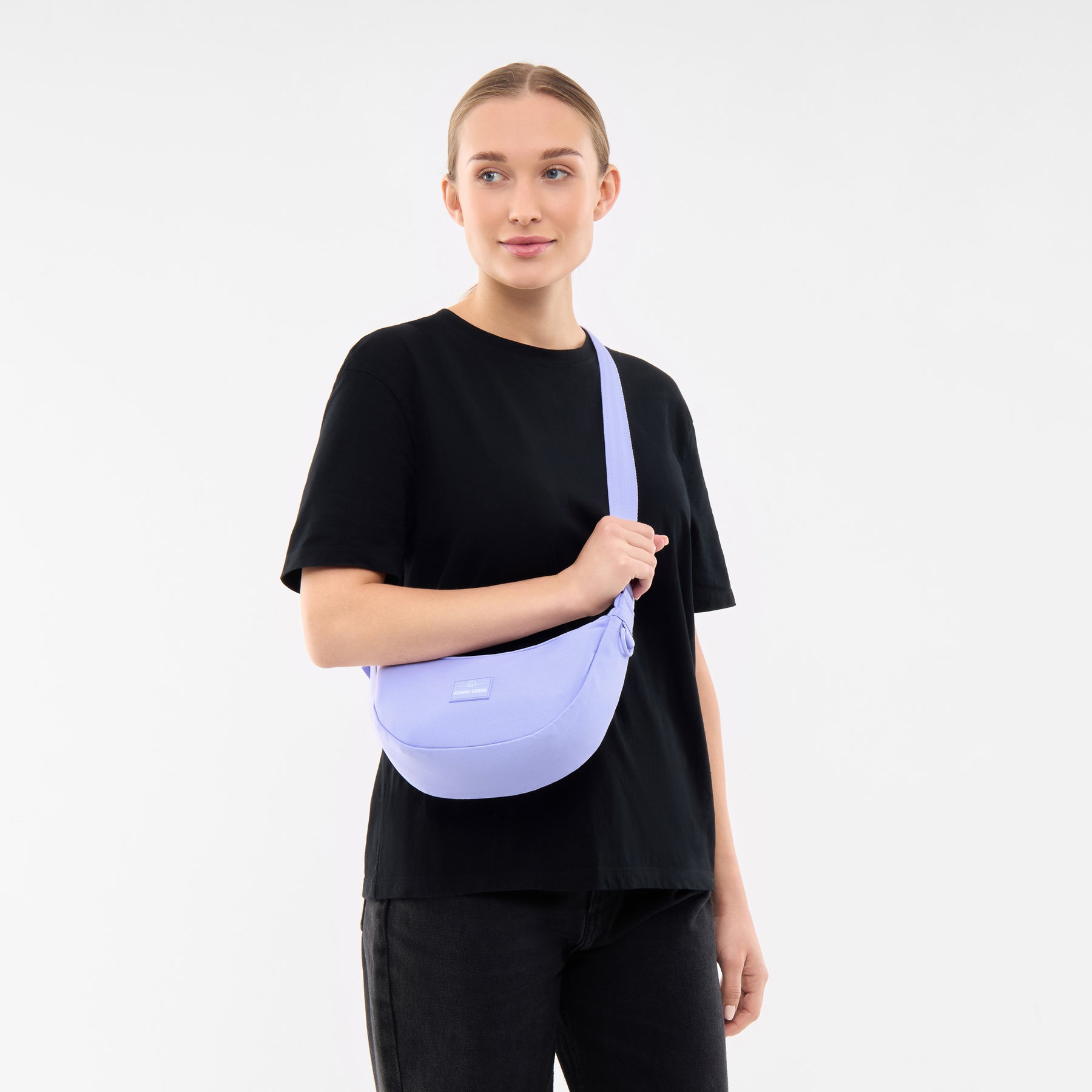 Frau trägt lila Half Moon Bag ‚Ally Small‘ von Johnny Urban über der Schulter, schwarze Kleidung