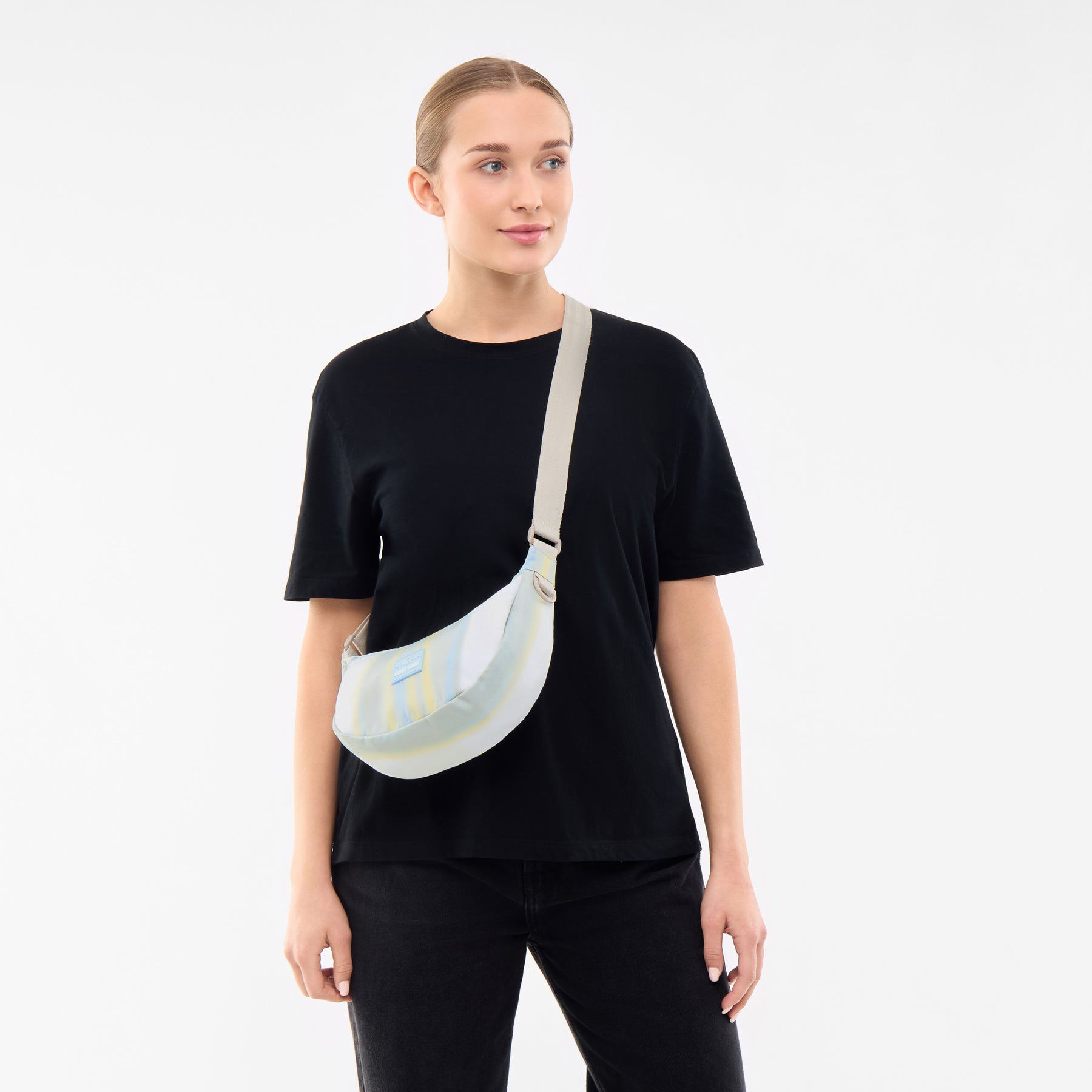 Frau trägt Half Moon Bag 'Ally Small' in sand mit gestreiftem Muster quer am Oberkörper