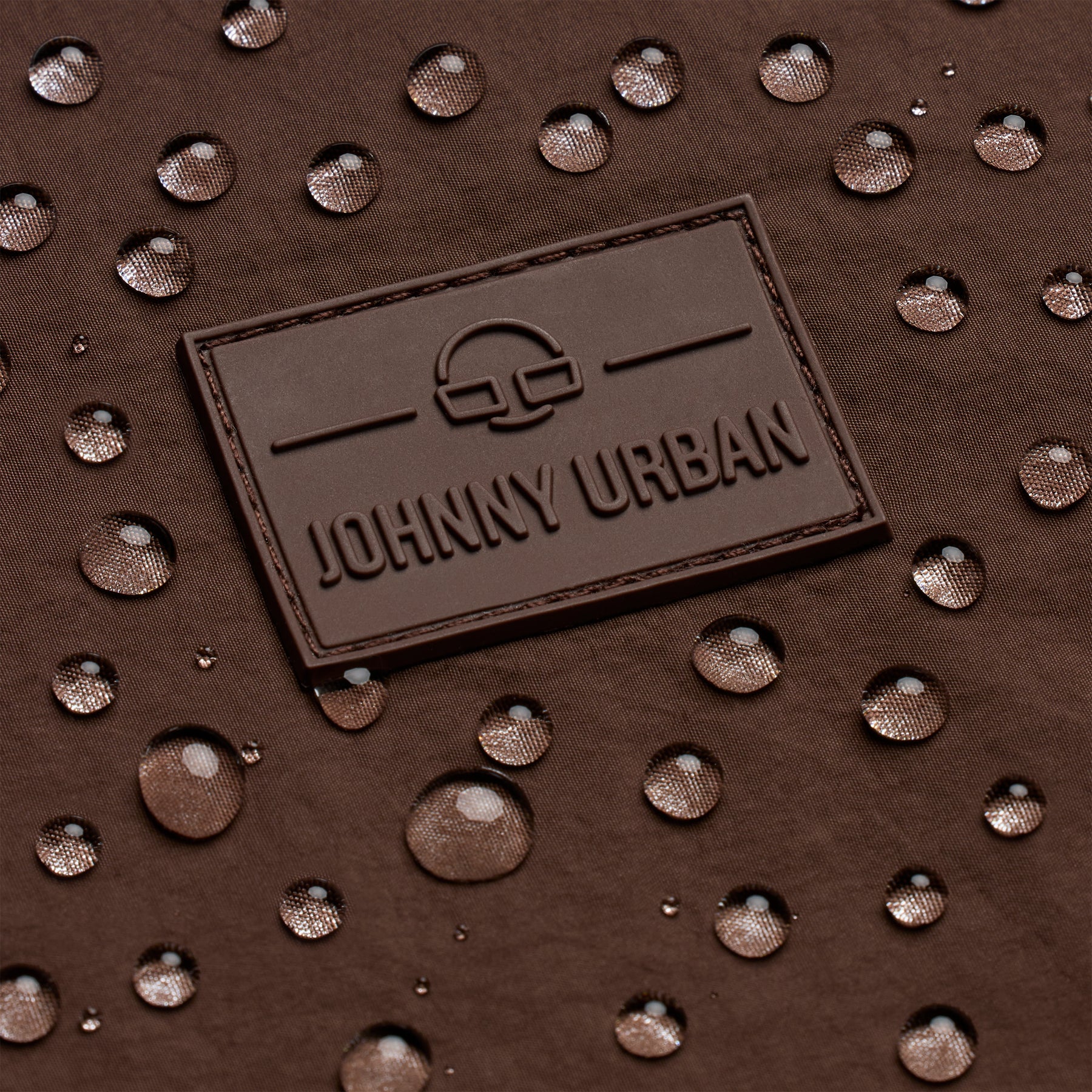 Johhny Urban Logo auf braunem, wasserabweisendem Stoff mit Wassertropfen
