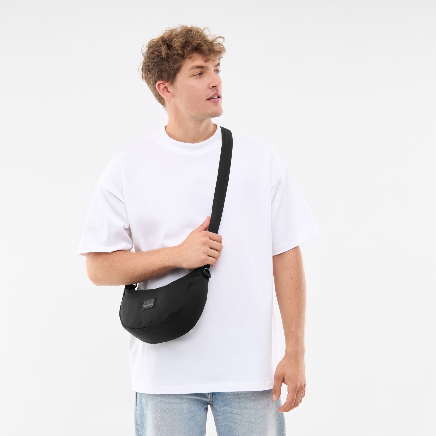 Mann trägt Johnny Urban Half Moon Bag 'Ally Small' in Schwarz quer über den Oberkörper