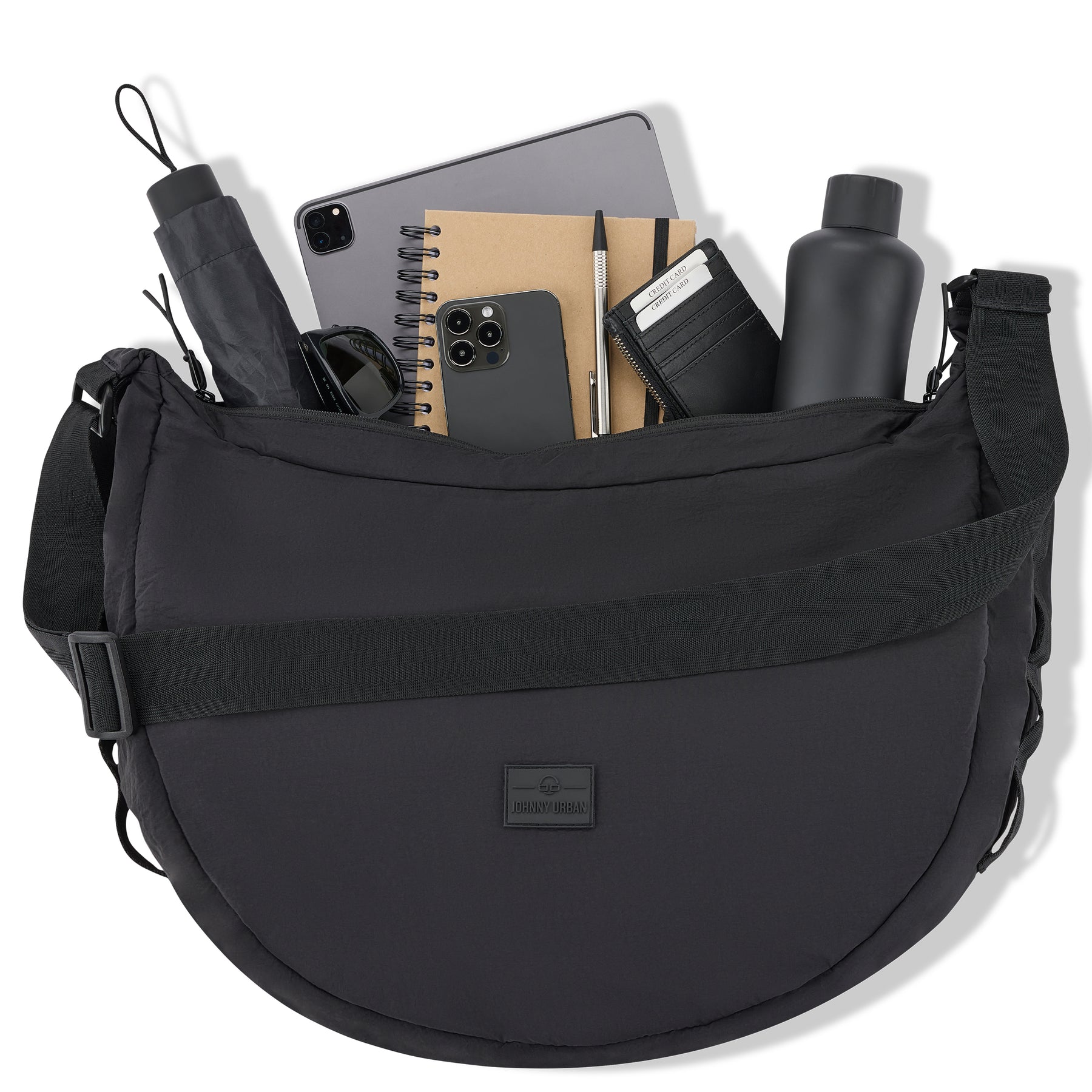Schwarze Half Moon Bag 'Kaia XL' mit Schultergurt gefüllt mit Tablet, Handy, Notizbuch, Stift, schwarzer Geldbörse, Wasserflasche, Regenschirm und Sonnenbrille
